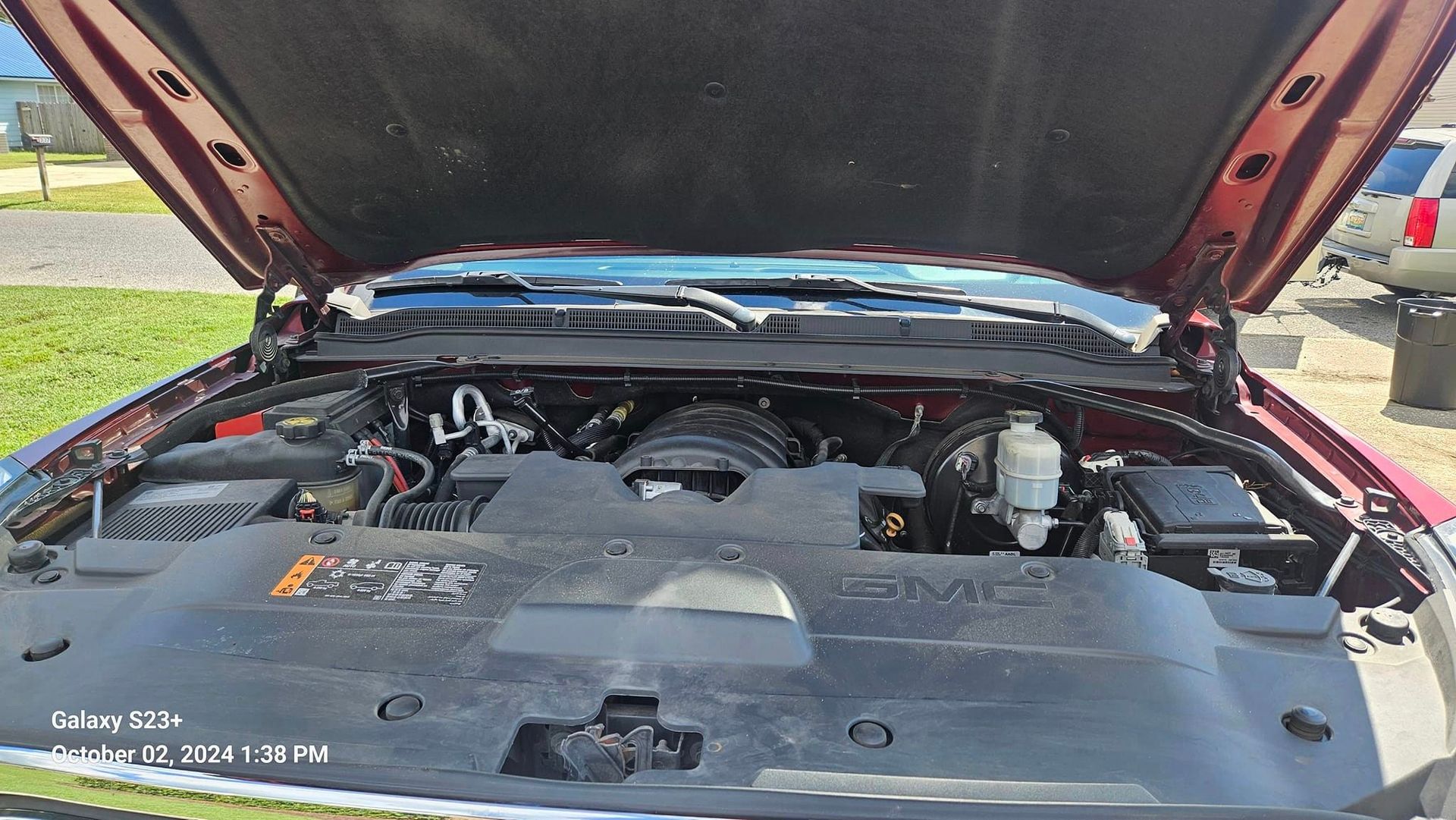 The engine of a red truck is shown with the hood open.