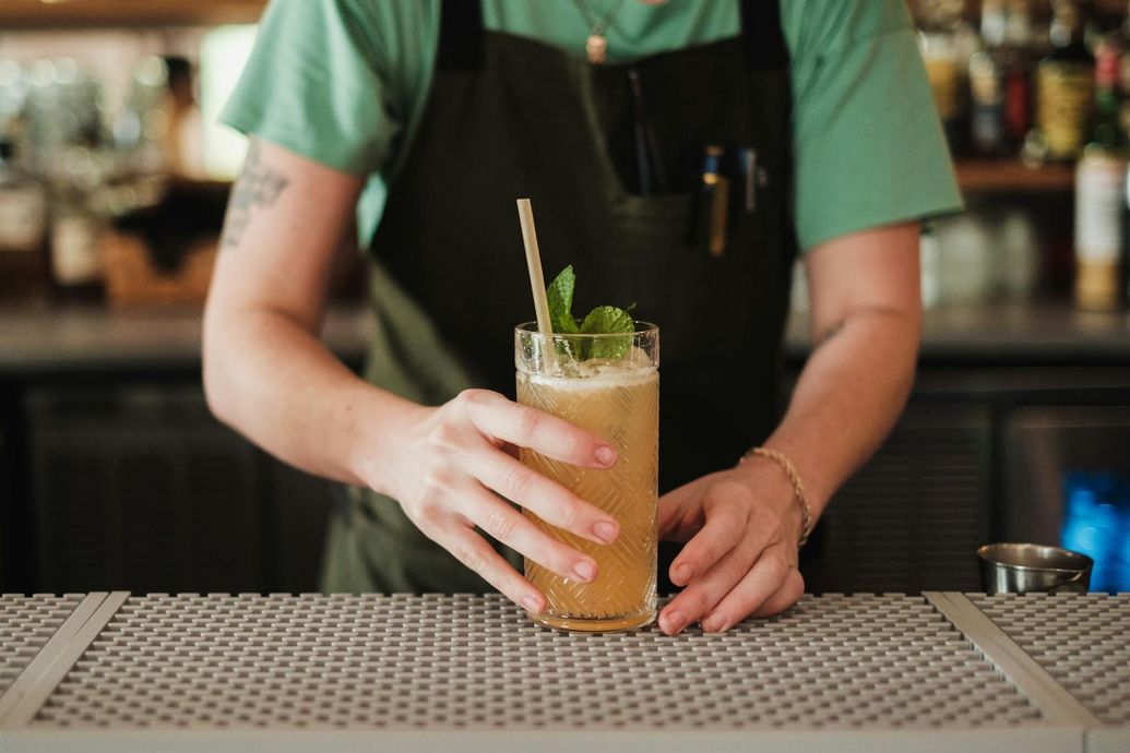 A bartender is preparing a drink on a bar counter.