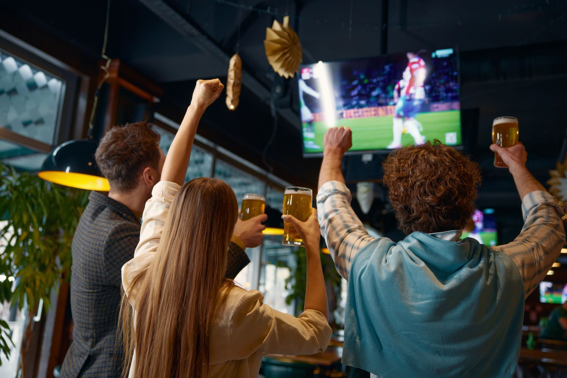 A group of people are watching a soccer game on a television in a bar.
