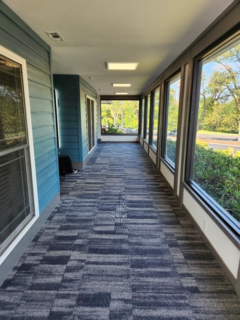A long hallway with a lot of windows and a carpeted floor.