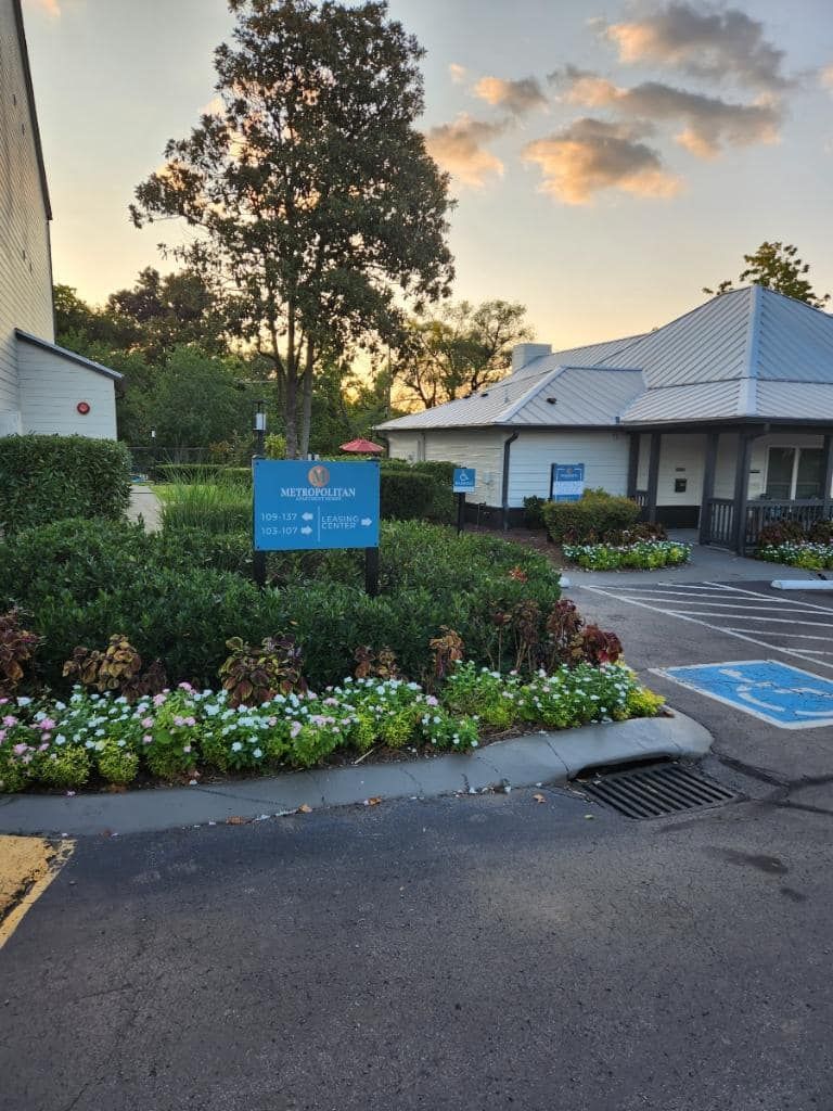 A blue sign is in front of a building with a handicapped parking spot.