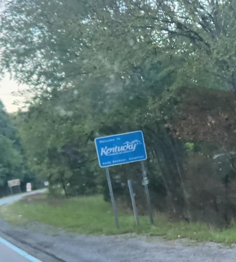 A blue kentucky sign on the side of a road