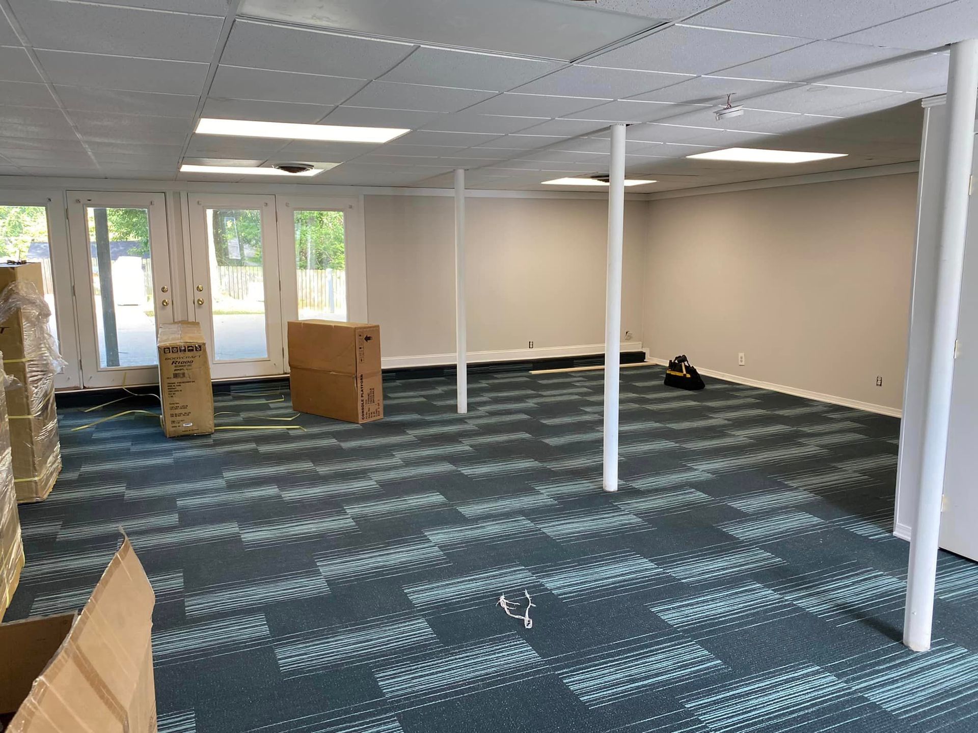 An empty room with a blue carpet and boxes on the floor.