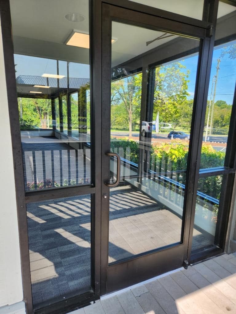 A door with a lot of windows and a reflection of trees in it.