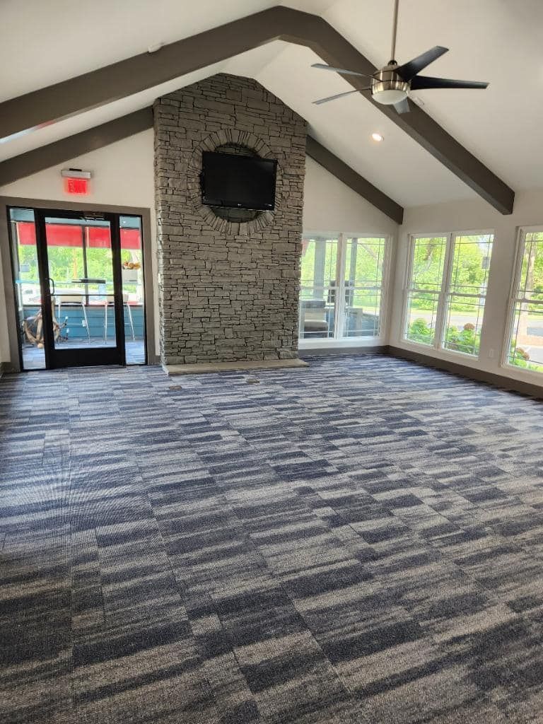 A large empty room with a ceiling fan and a fireplace.