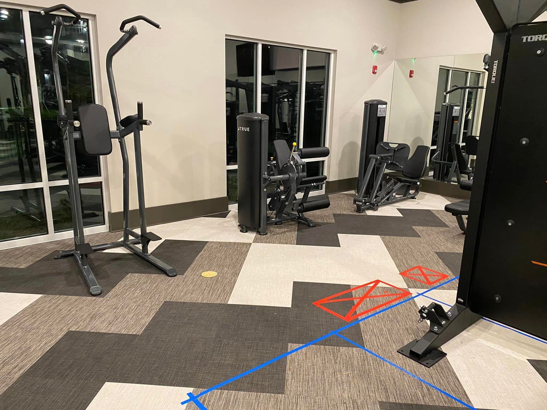 A gym with a lot of exercise equipment and a blue line on the floor.