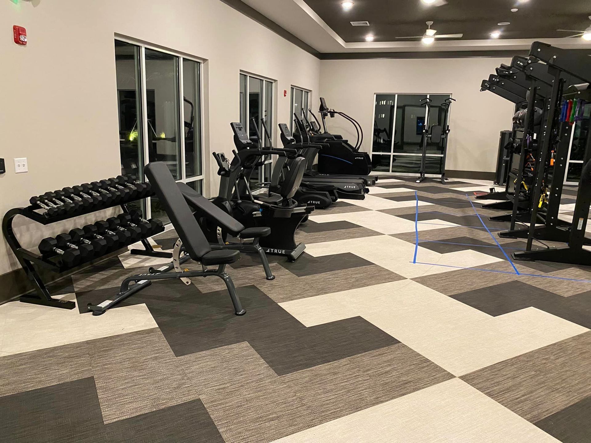 A gym with a lot of exercise equipment and a checkered floor.