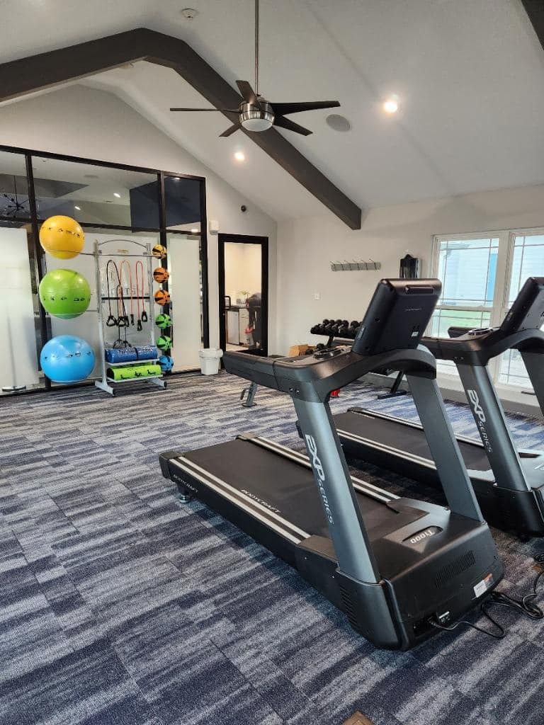 A gym with two treadmills and a ceiling fan.