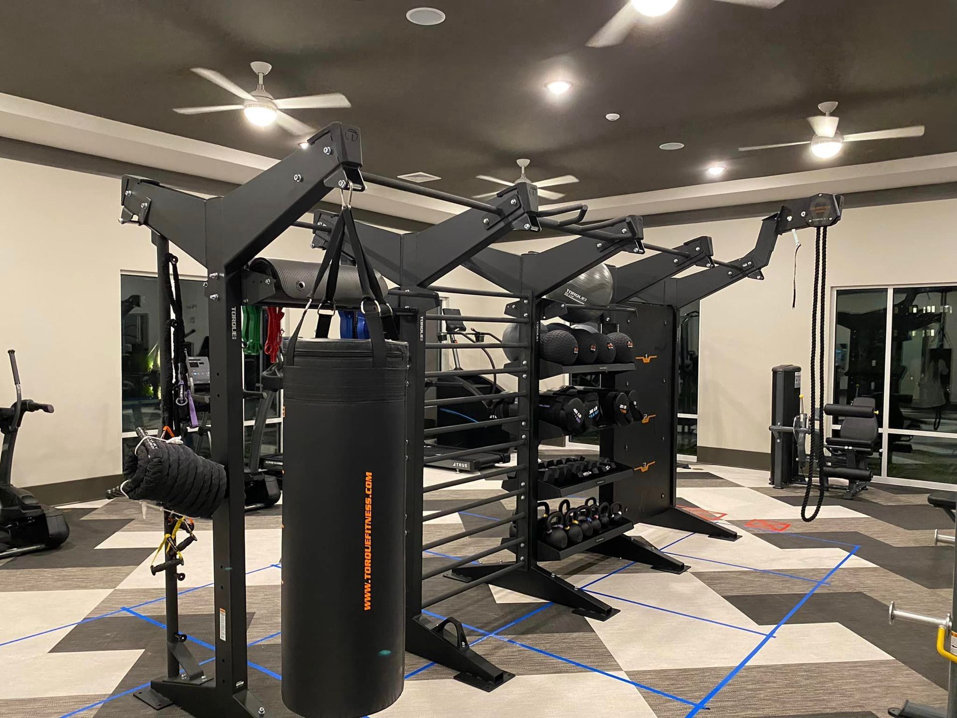 A gym with a lot of equipment and a boxing bag.