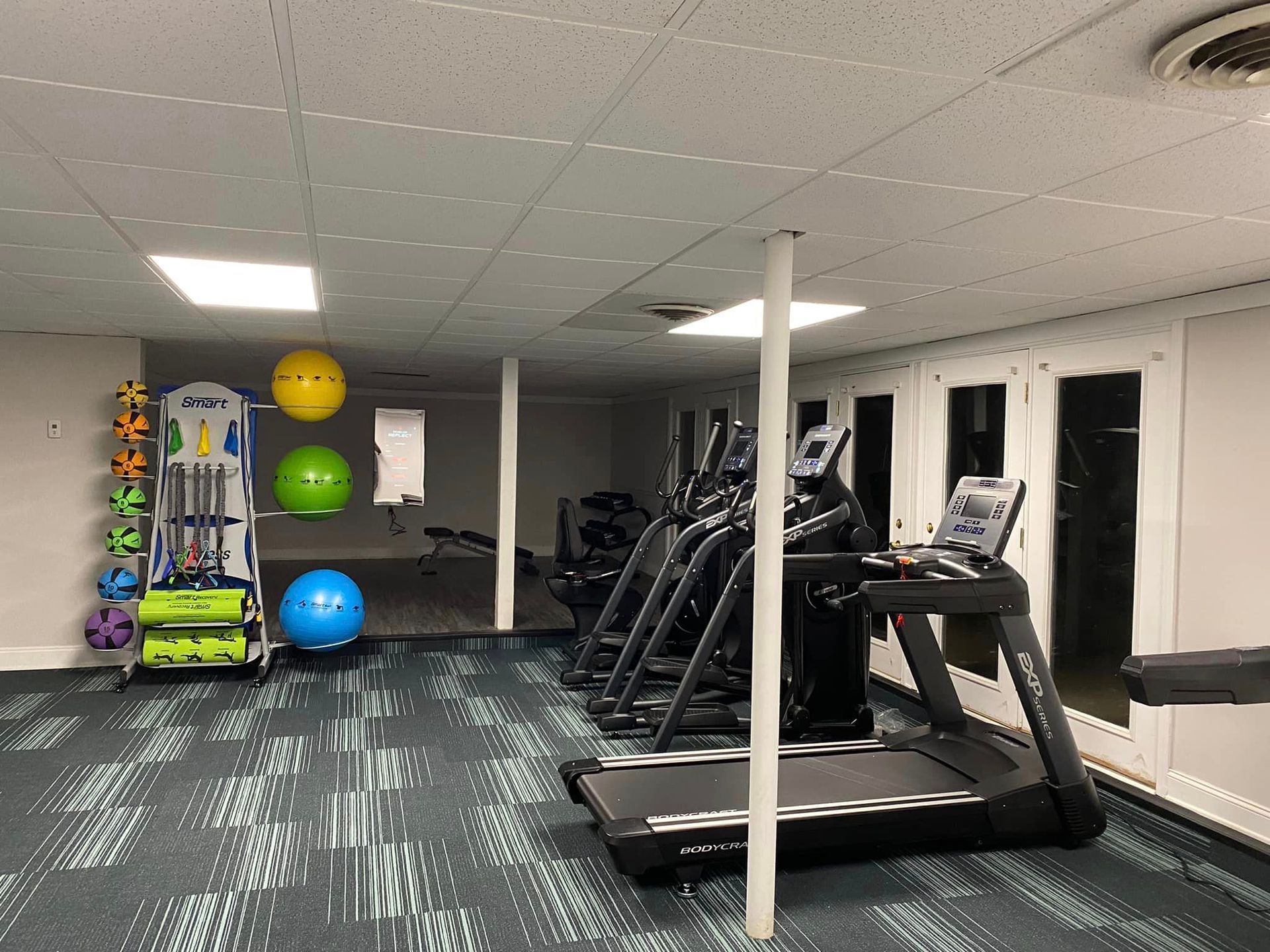 A gym with treadmills , ellipticals , and exercise balls.