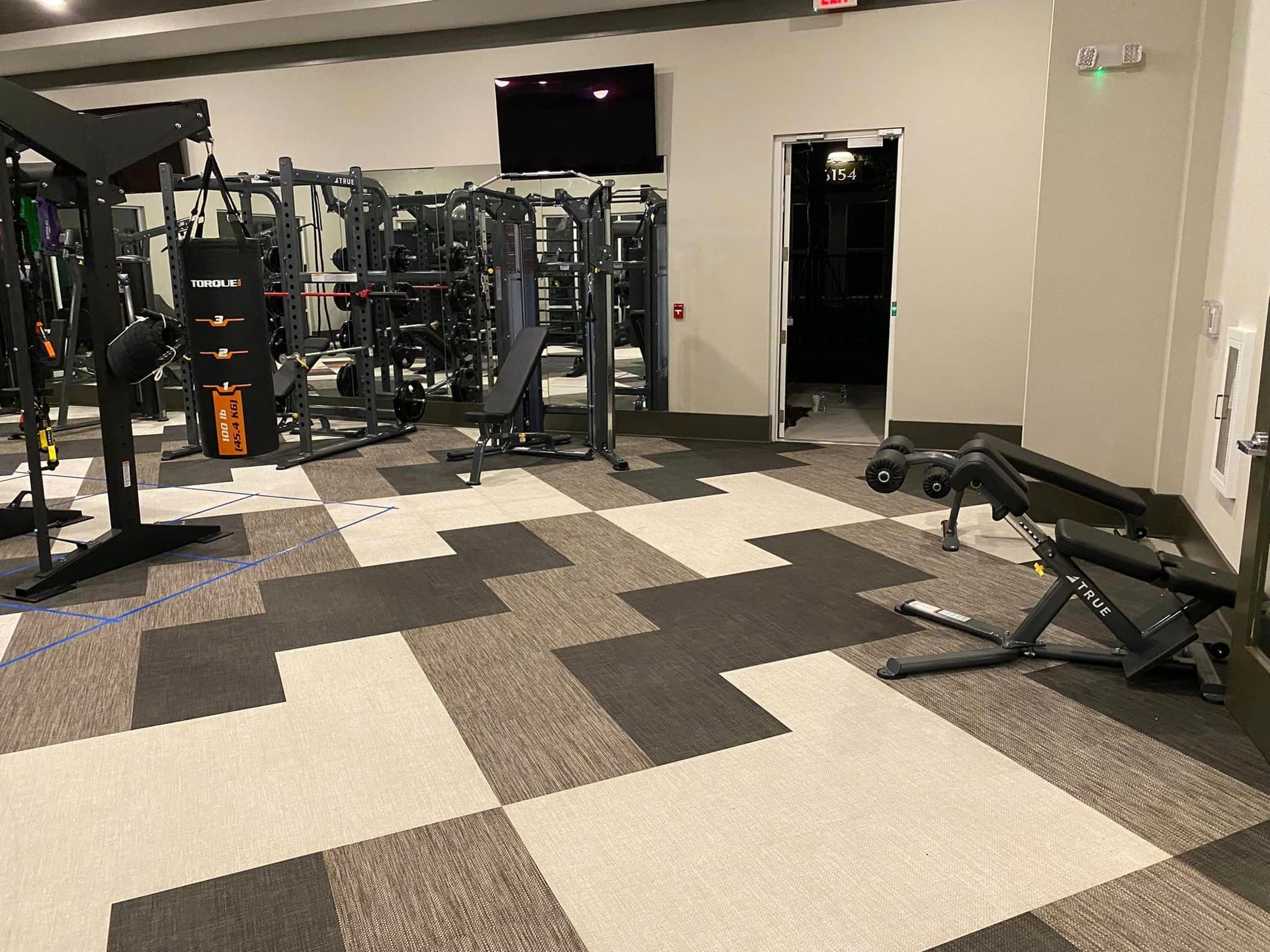 A gym with a lot of exercise equipment and a checkered floor.