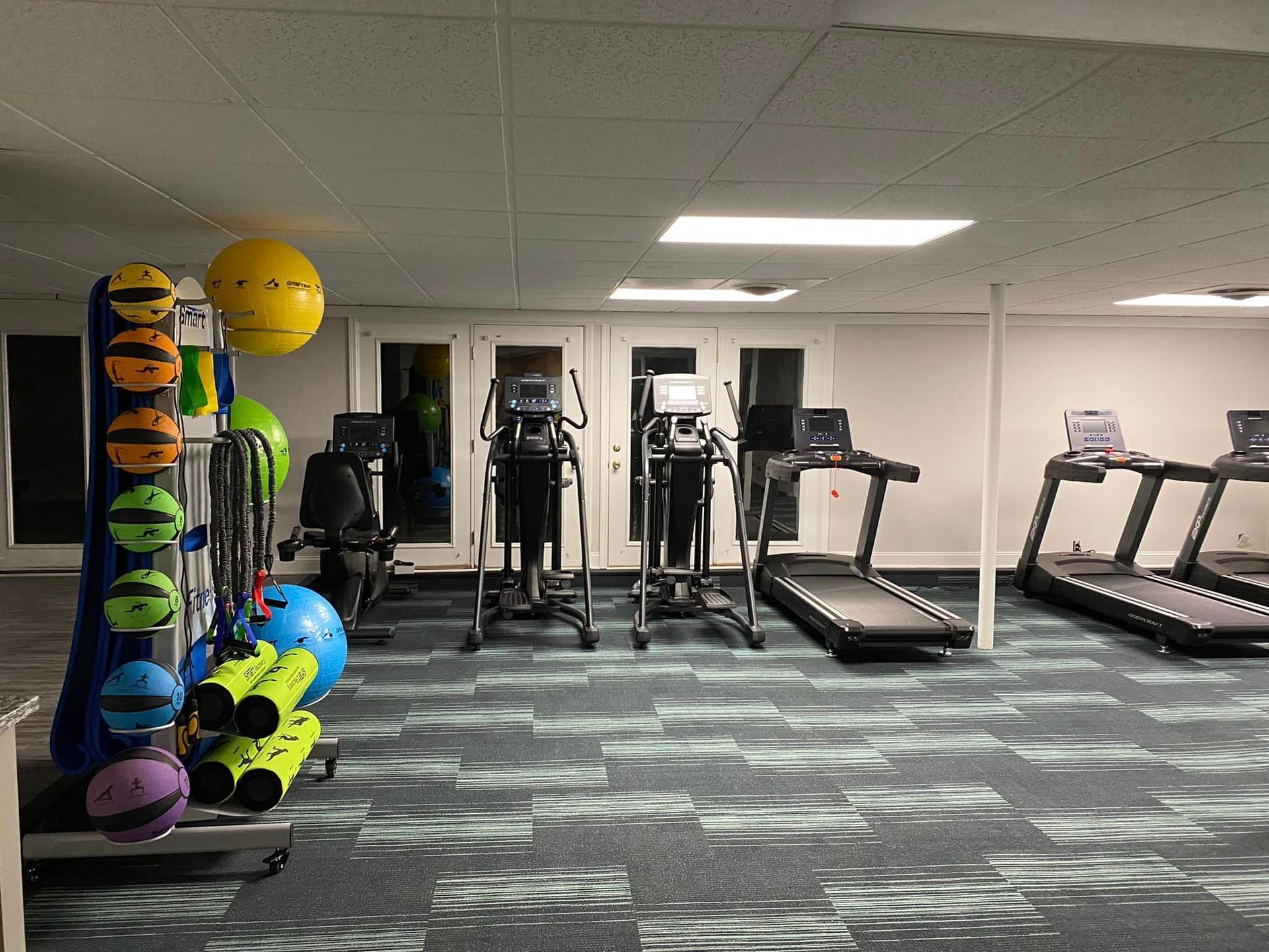 A gym filled with treadmills , ellipticals , and other exercise equipment.
