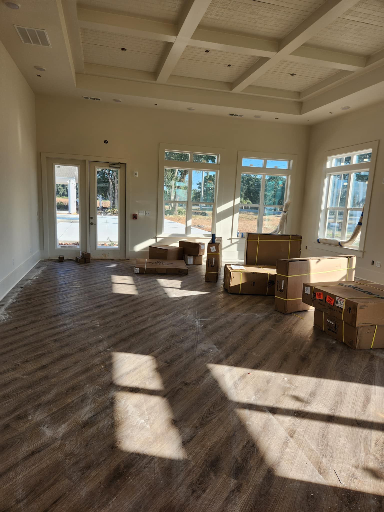 A large empty room with boxes on the floor and a lot of windows.