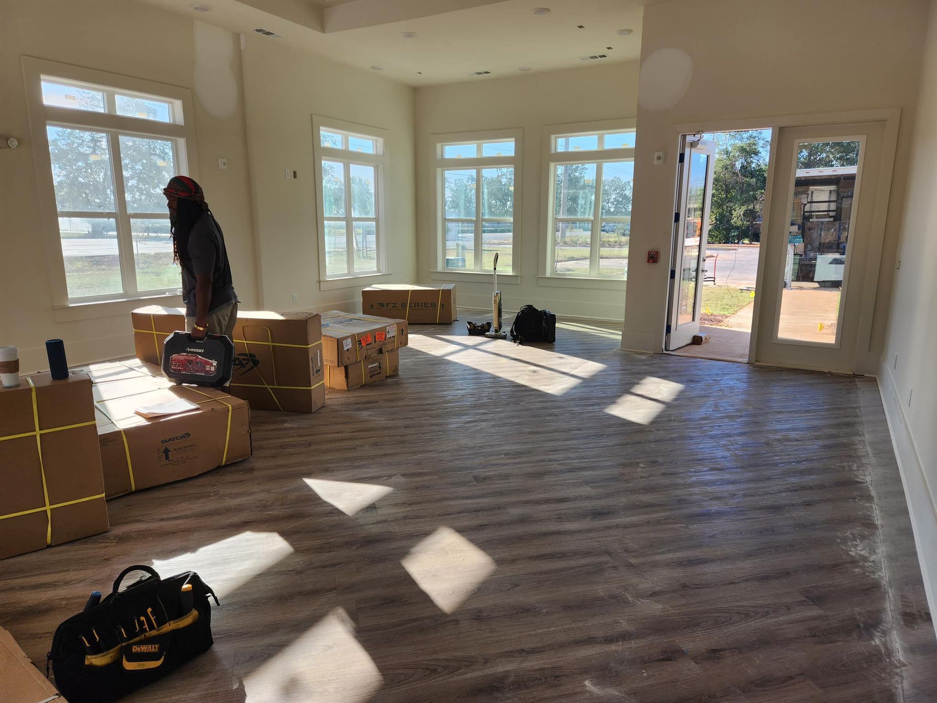 A man is standing in an empty room with boxes on the floor.