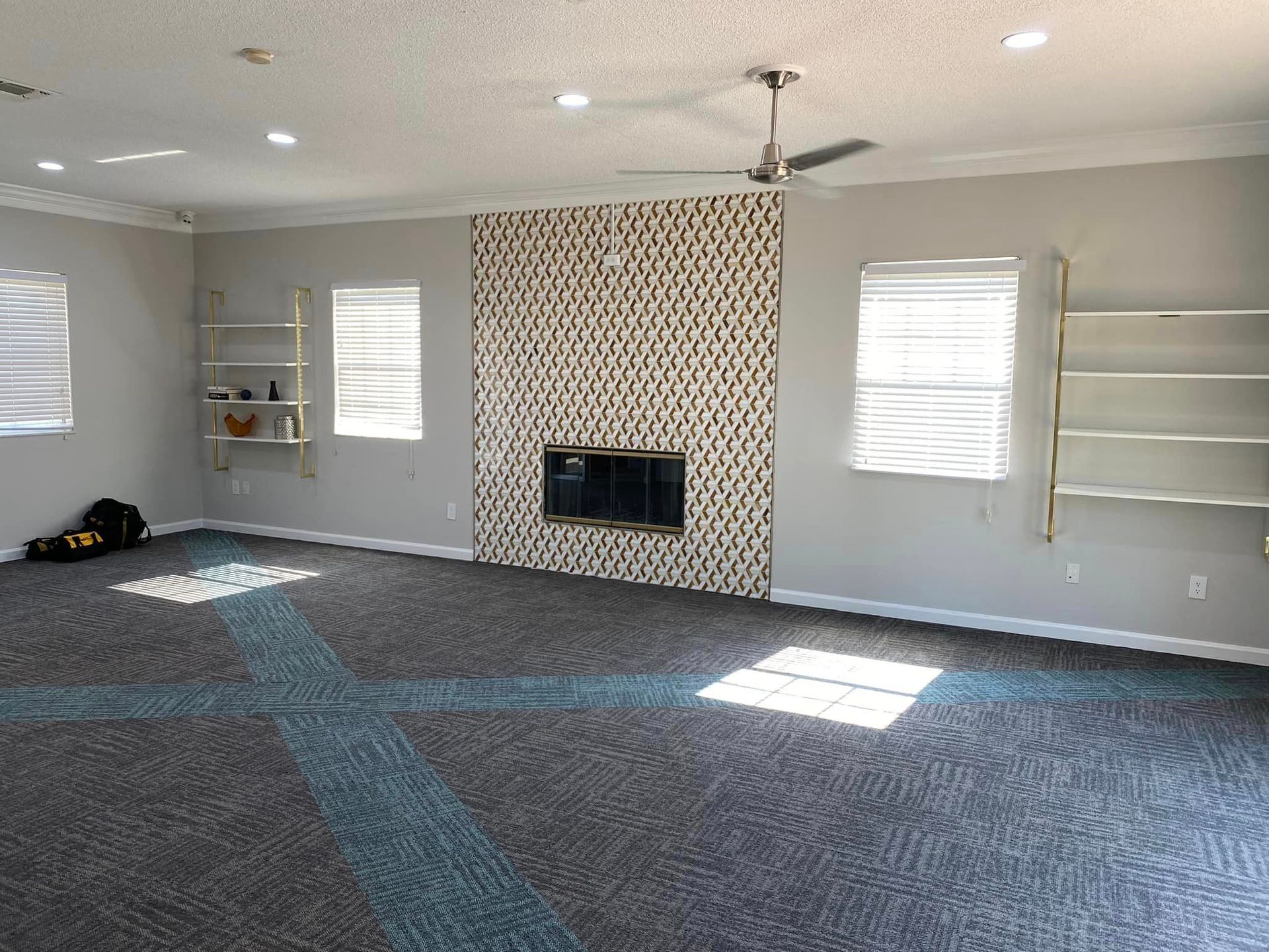 An empty living room with a fireplace and a ceiling fan.