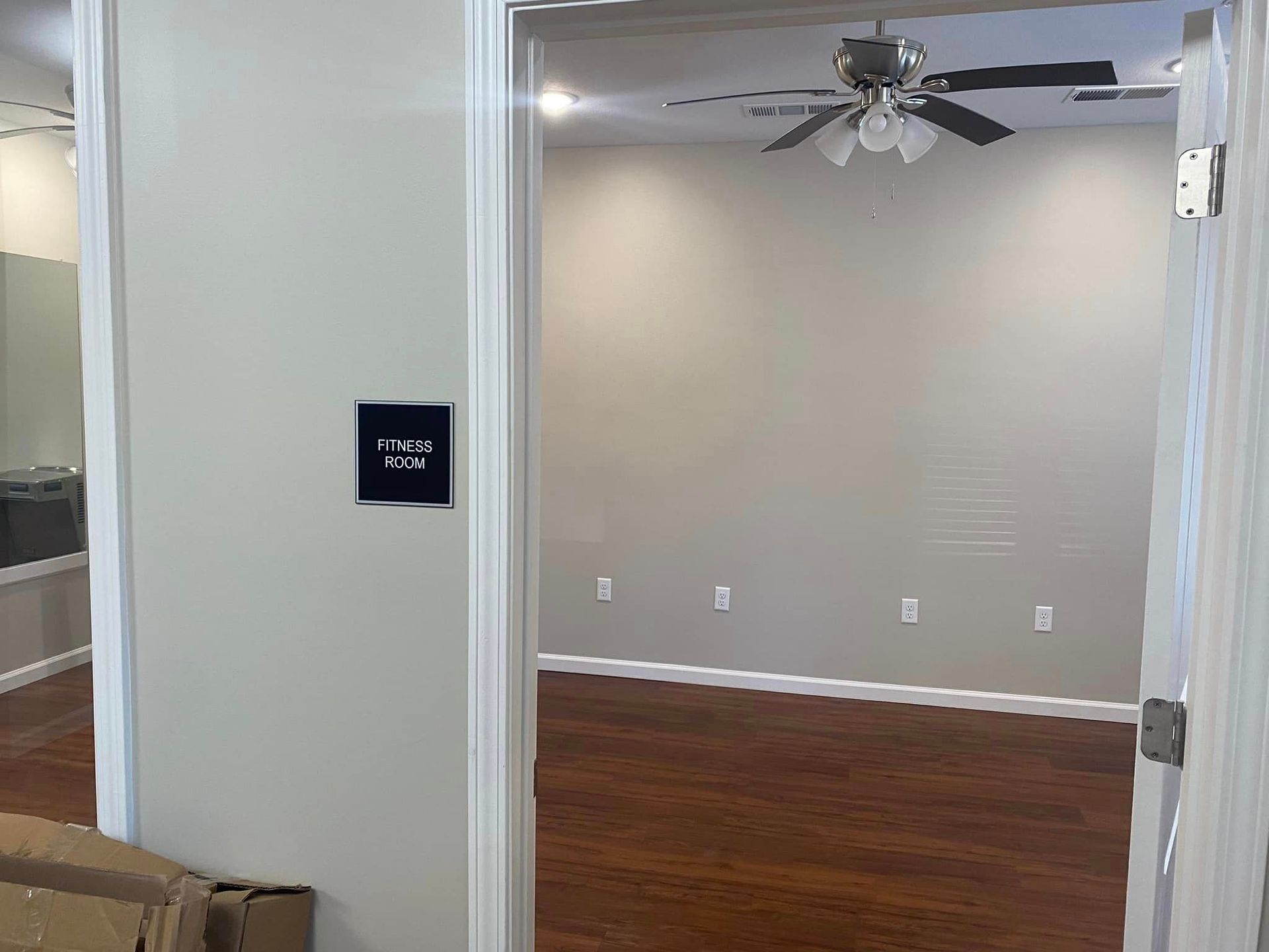 An empty room with hardwood floors and a ceiling fan.