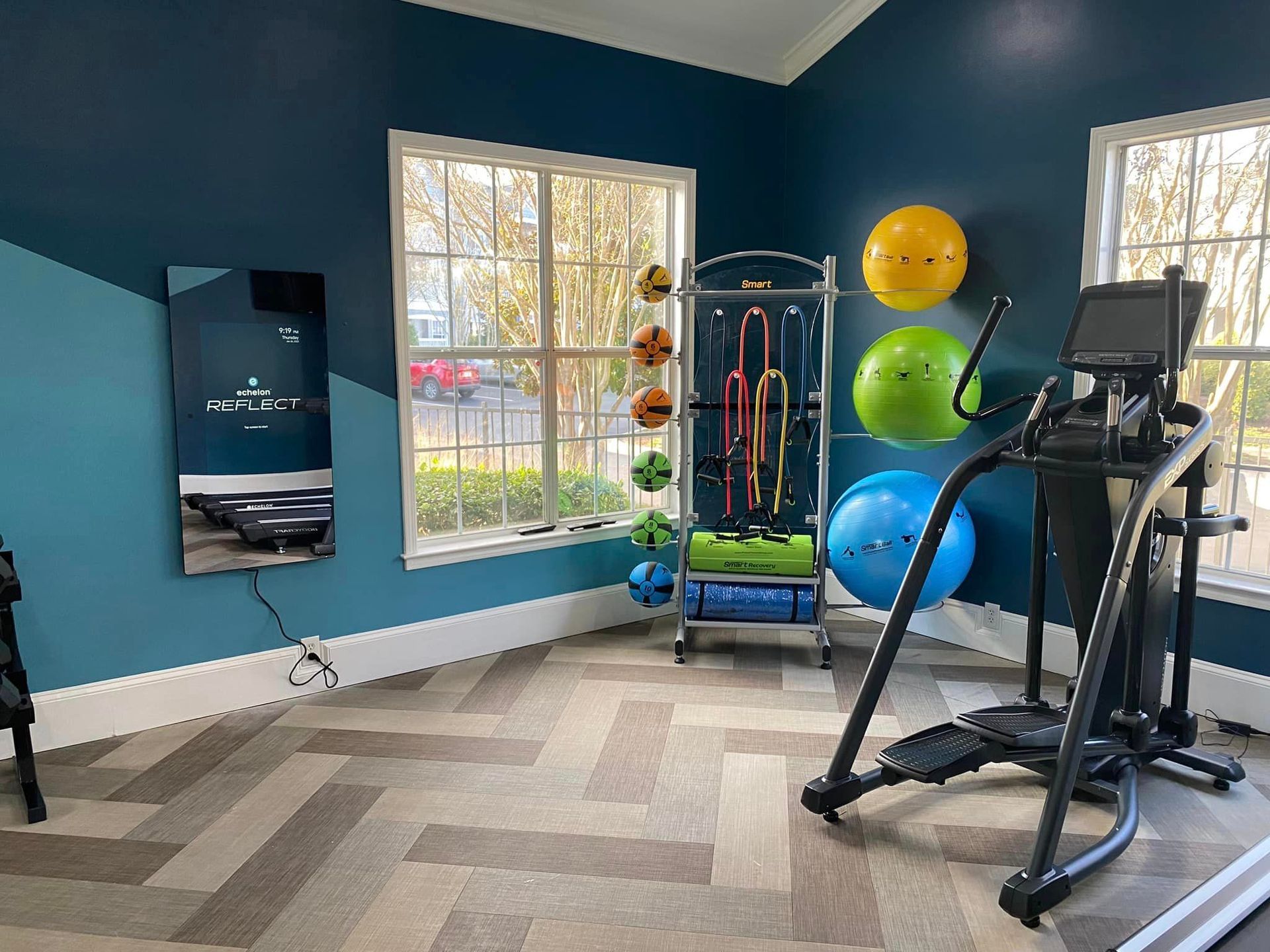A gym with a treadmill , exercise balls , and a mirror.