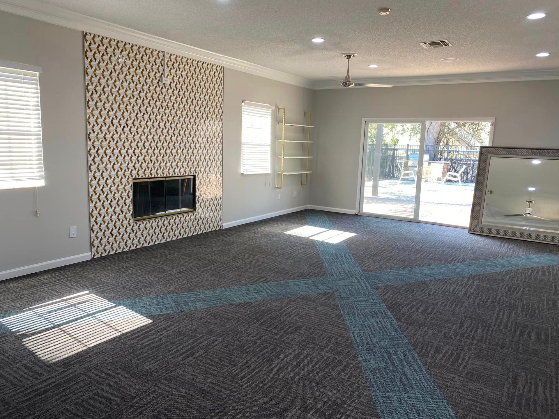 An empty living room with a fireplace and sliding glass doors.