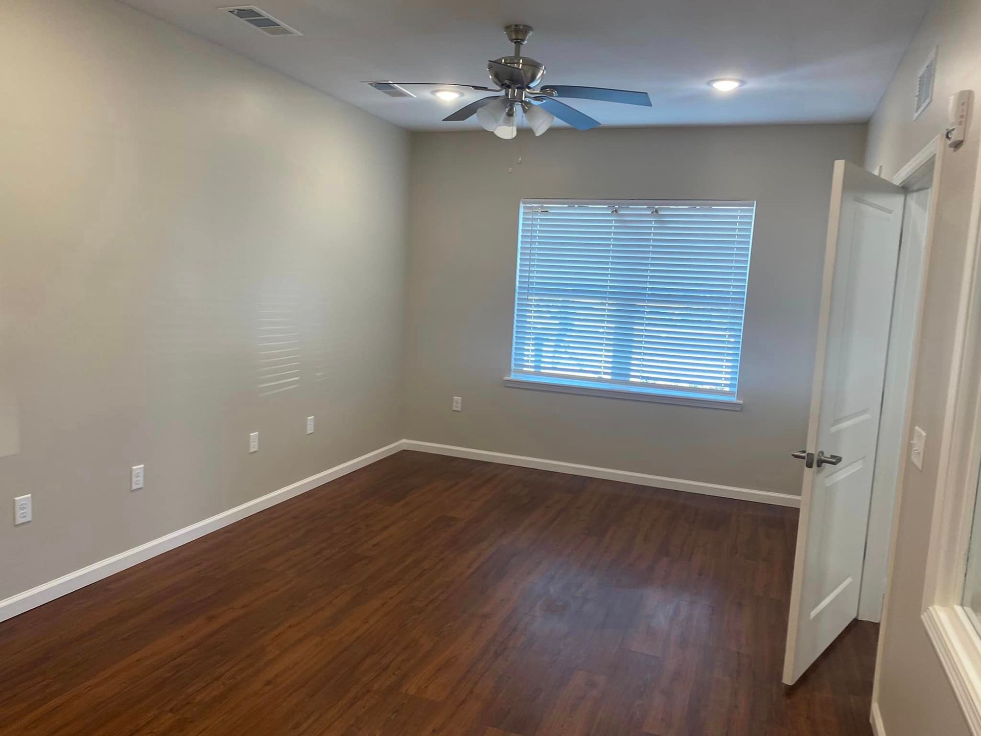 An empty room with hardwood floors and a ceiling fan.