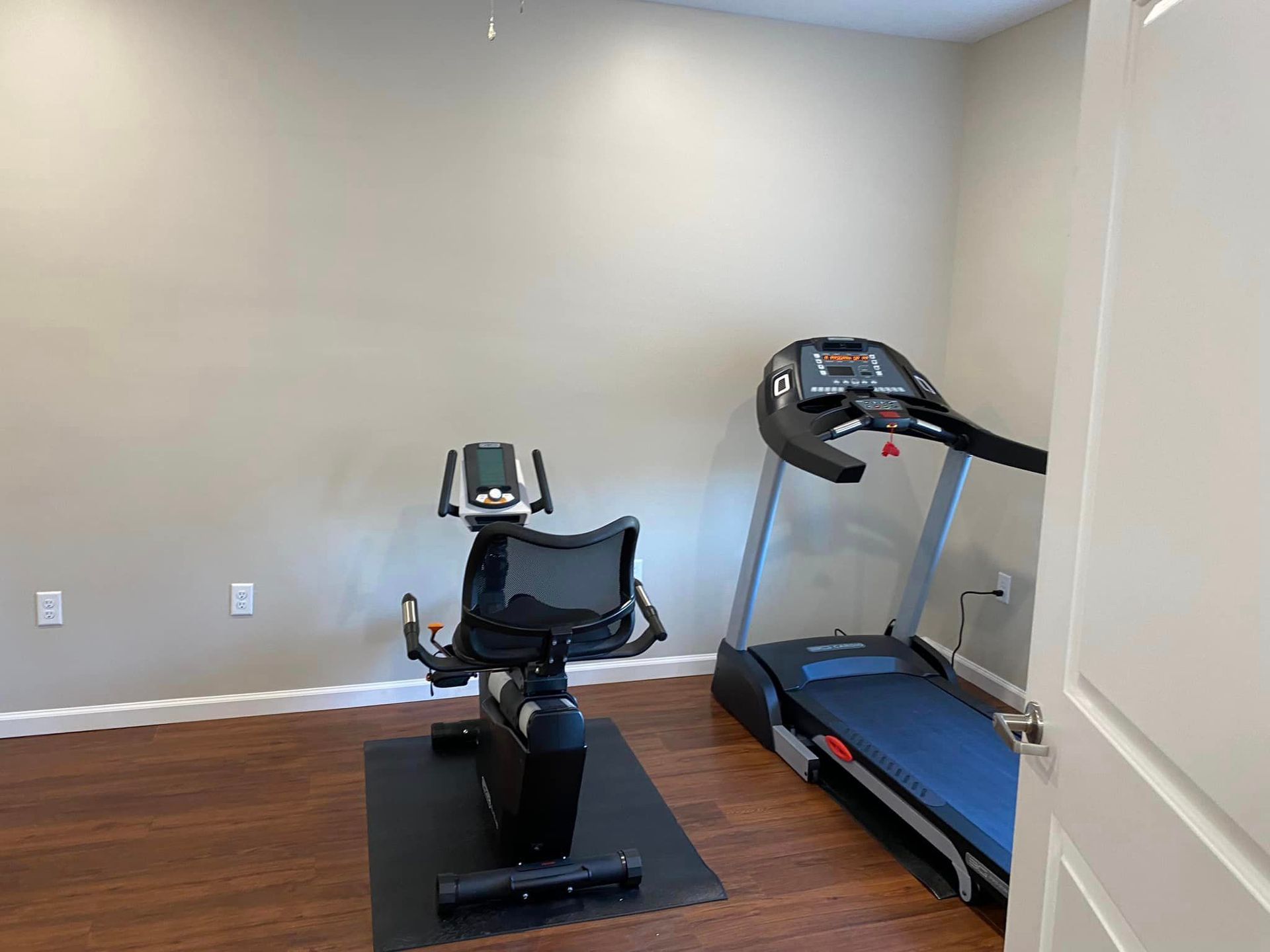 There is a treadmill and an exercise bike in the room.