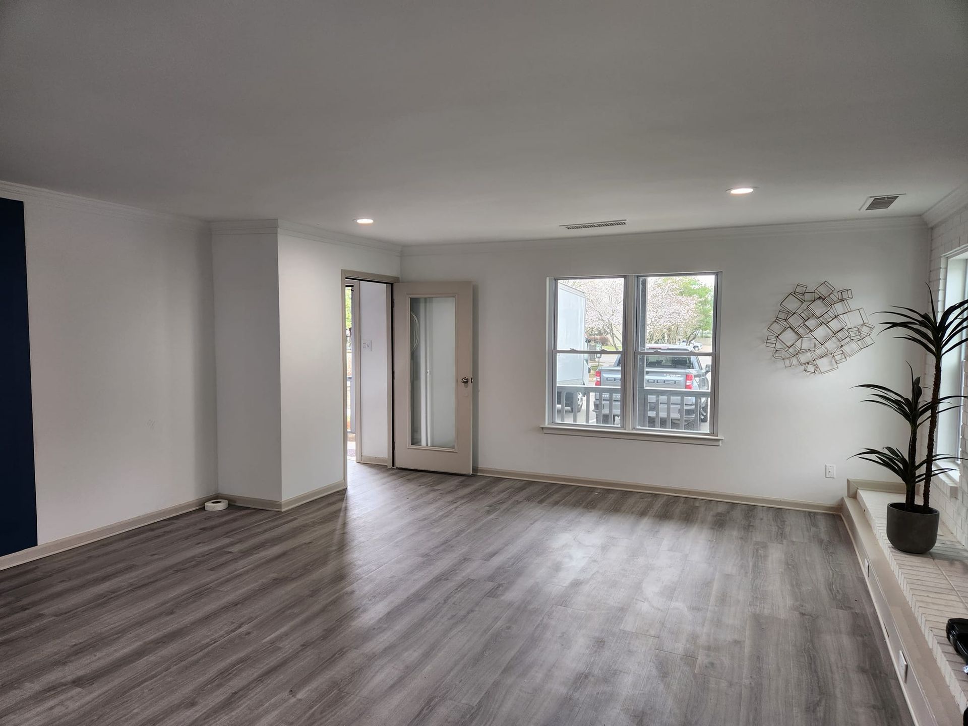 An empty living room with hardwood floors and white walls.