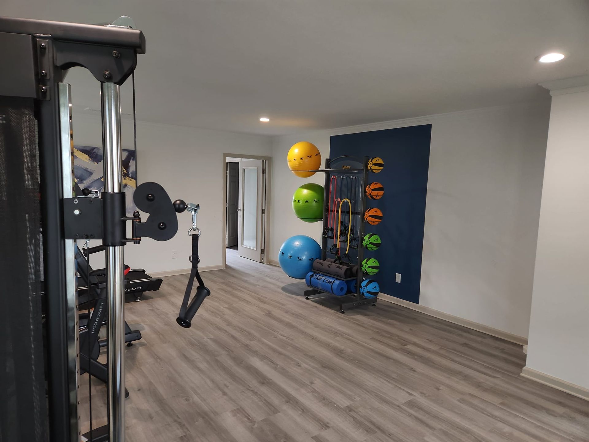 A gym with a lot of equipment and balls on the wall.