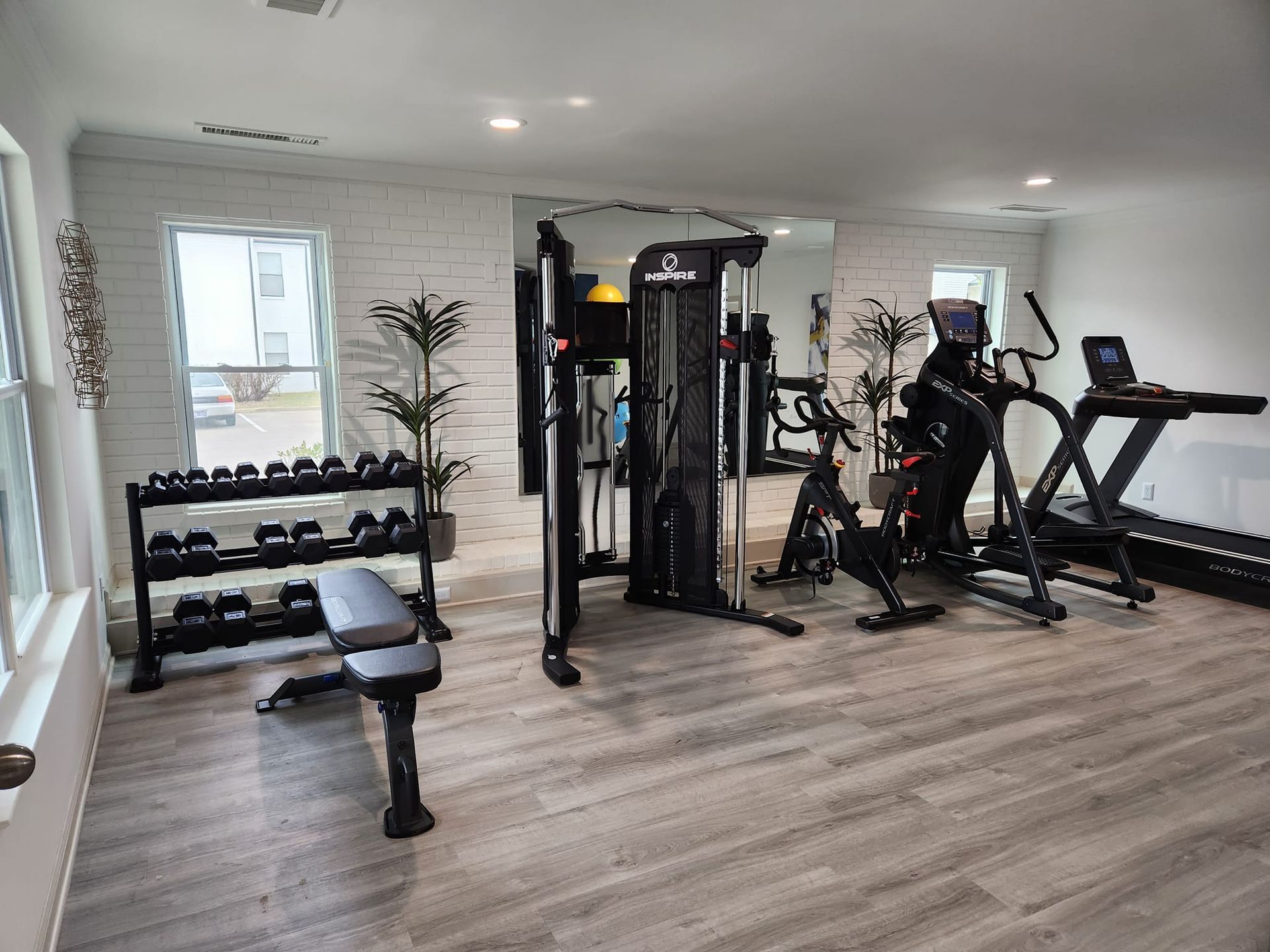 A gym with a treadmill , exercise bike , dumbbells and a bench.