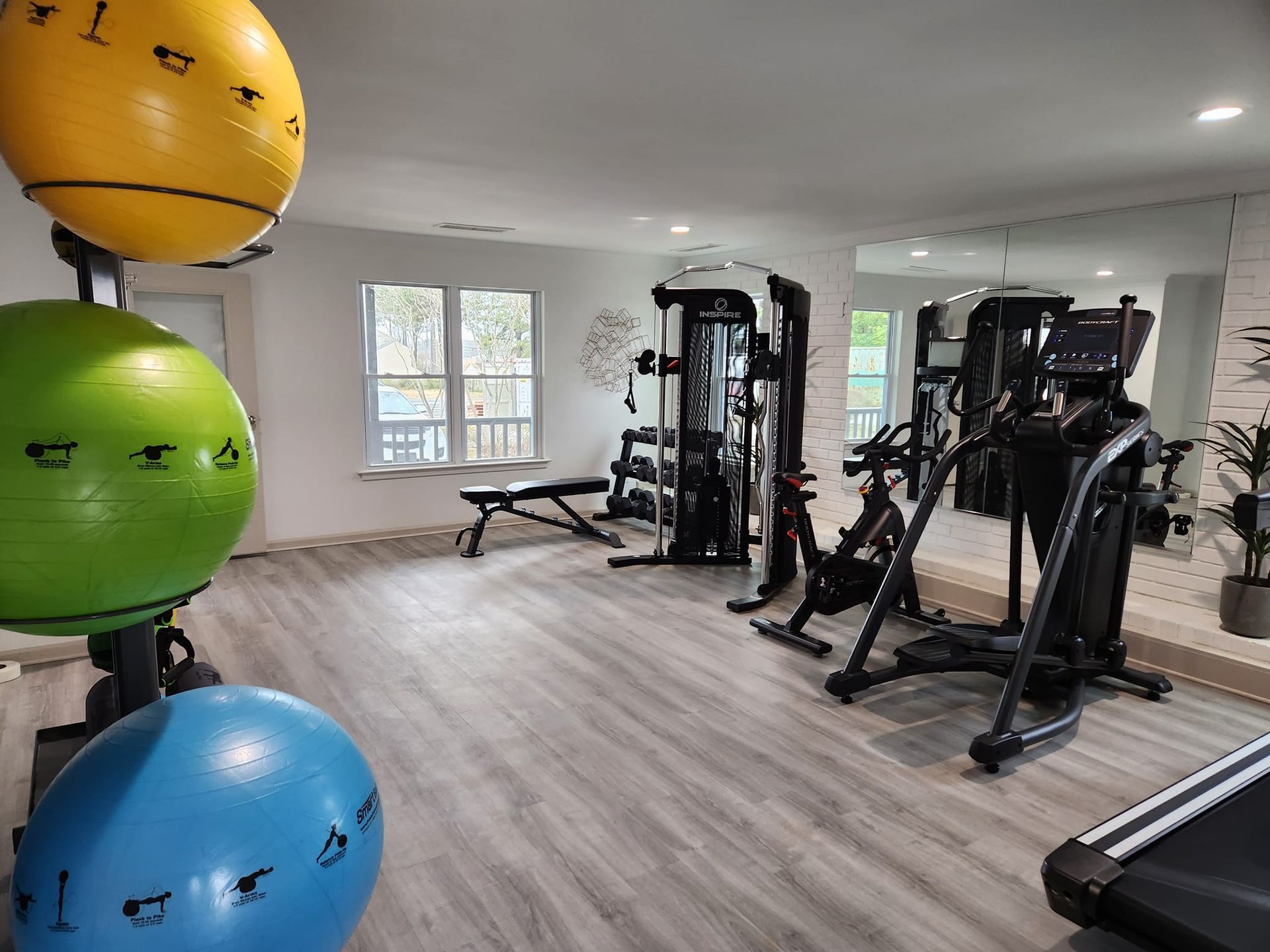 A gym with a treadmill , exercise balls , and a bicycle.