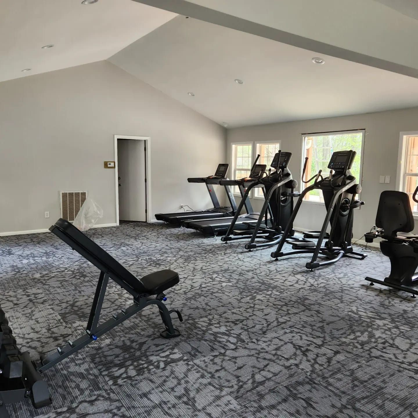 A gym with treadmills , ellipticals , and a bench.