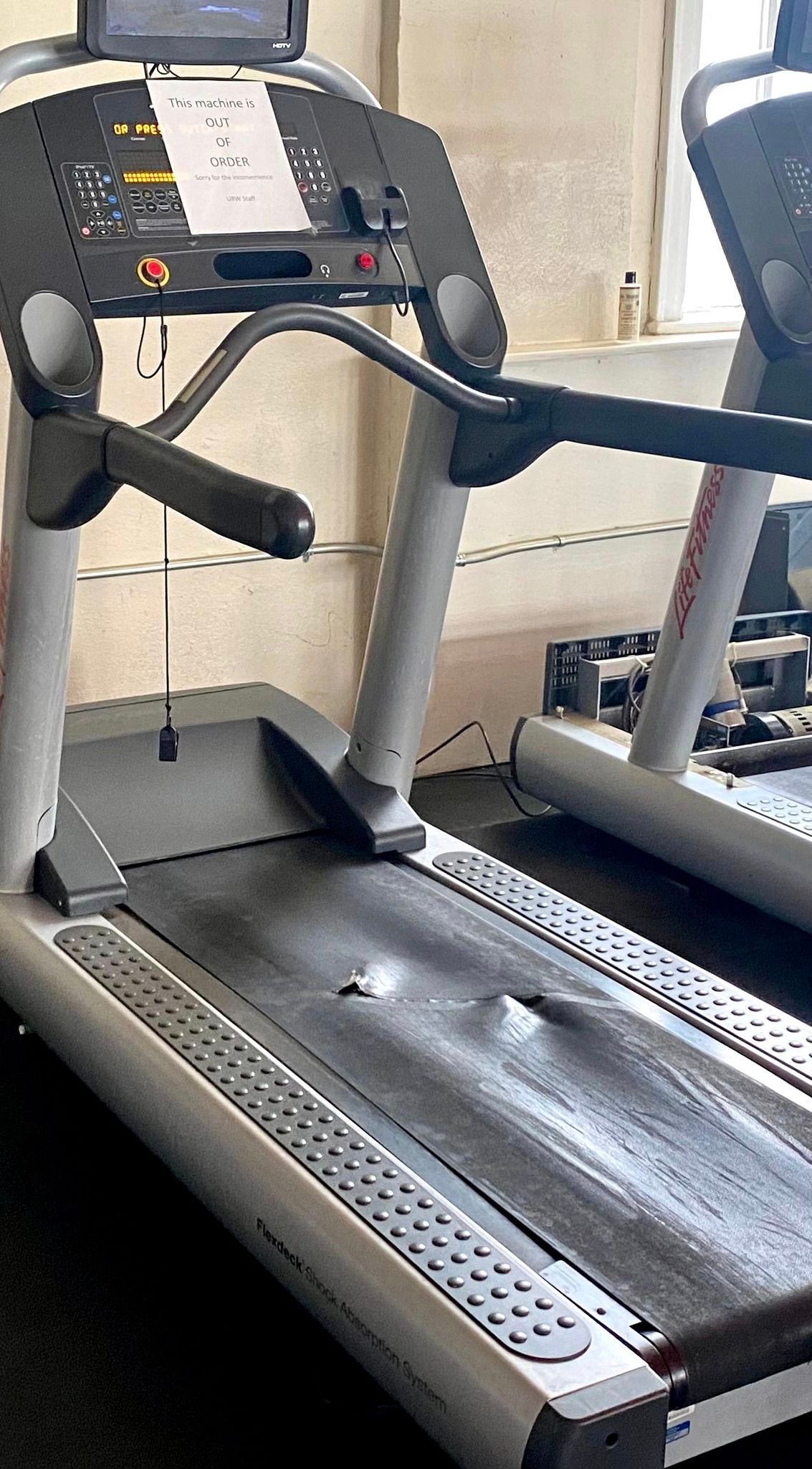 A treadmill is sitting on the floor in a gym.