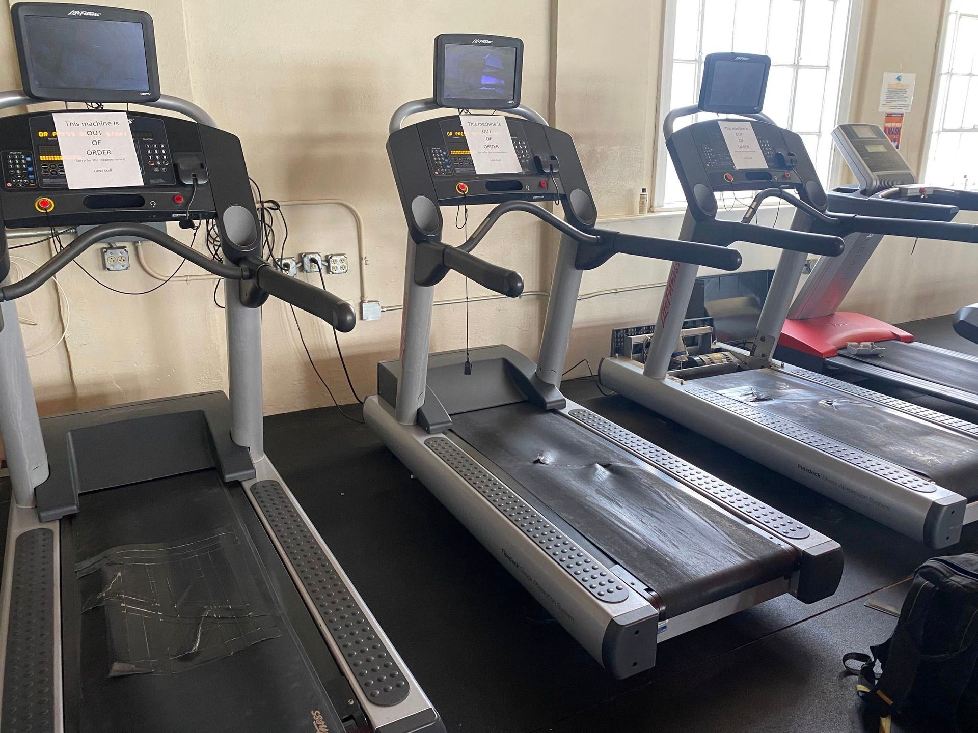A row of treadmills are lined up in a gym.