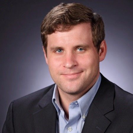 A man in a suit and tie is smiling for the camera.