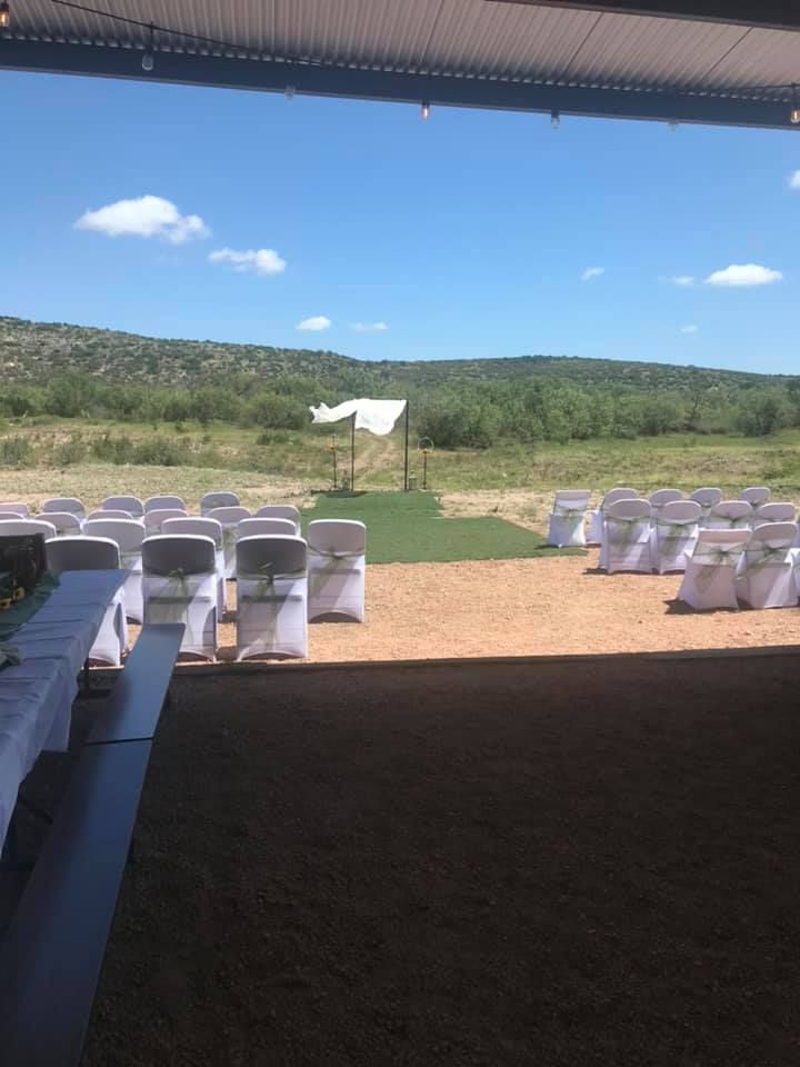 A row of white chairs are set up for a wedding ceremony