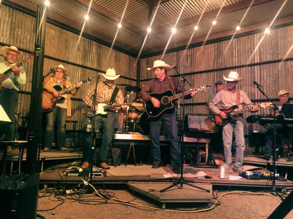 A group of cowboys are playing guitars and singing on a stage.