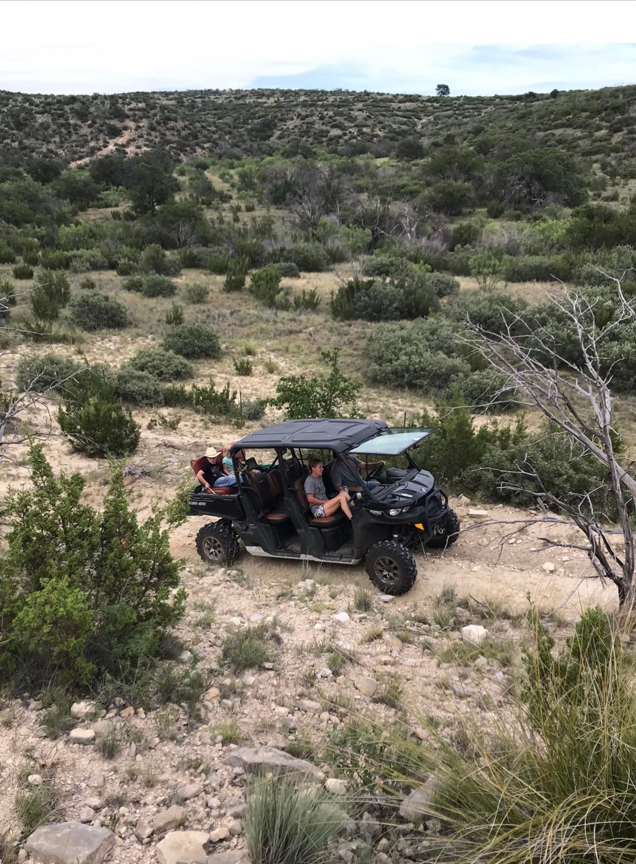 A group of people are riding a atv in the desert.