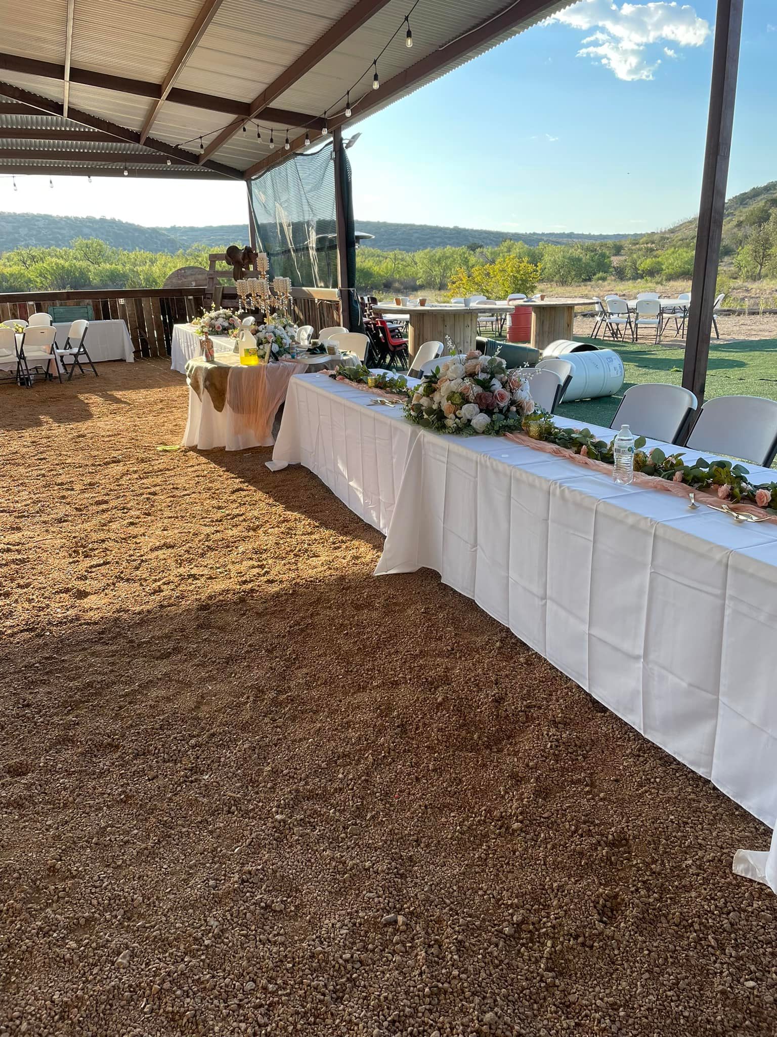 A long table with flowers on it is sitting under a canopy.