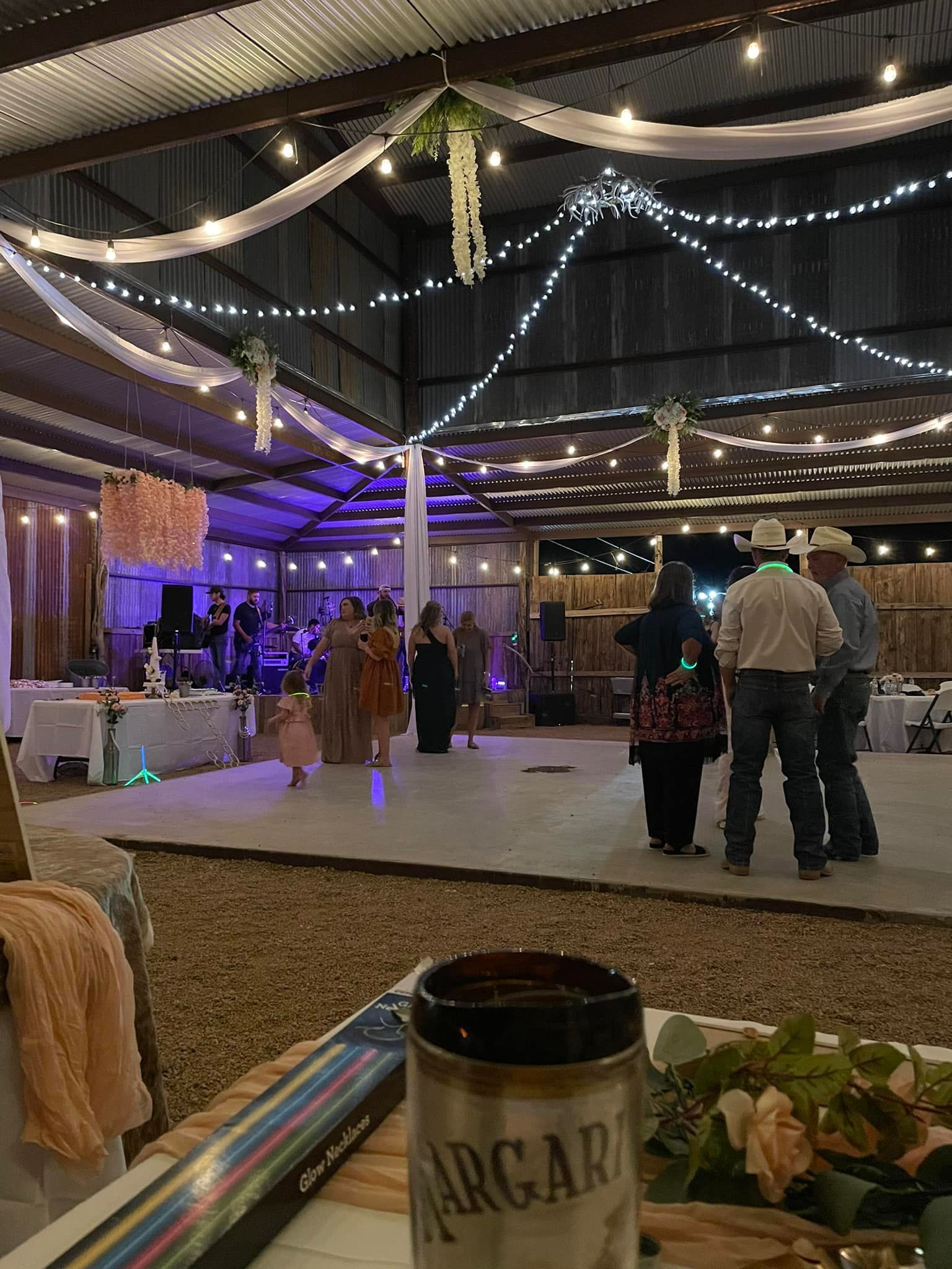 A group of people are dancing in a large room at a wedding reception.