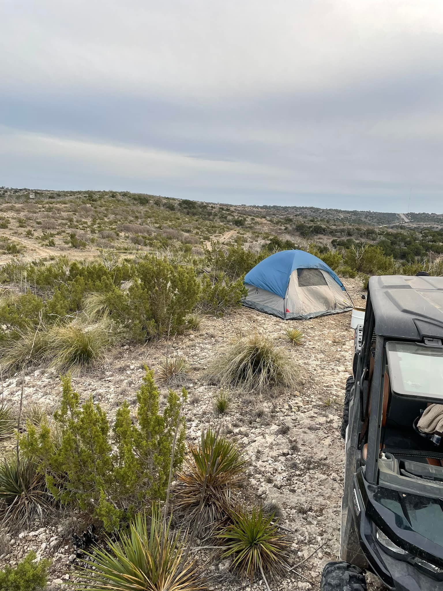 A tent is sitting in the middle of a desert next to a truck.