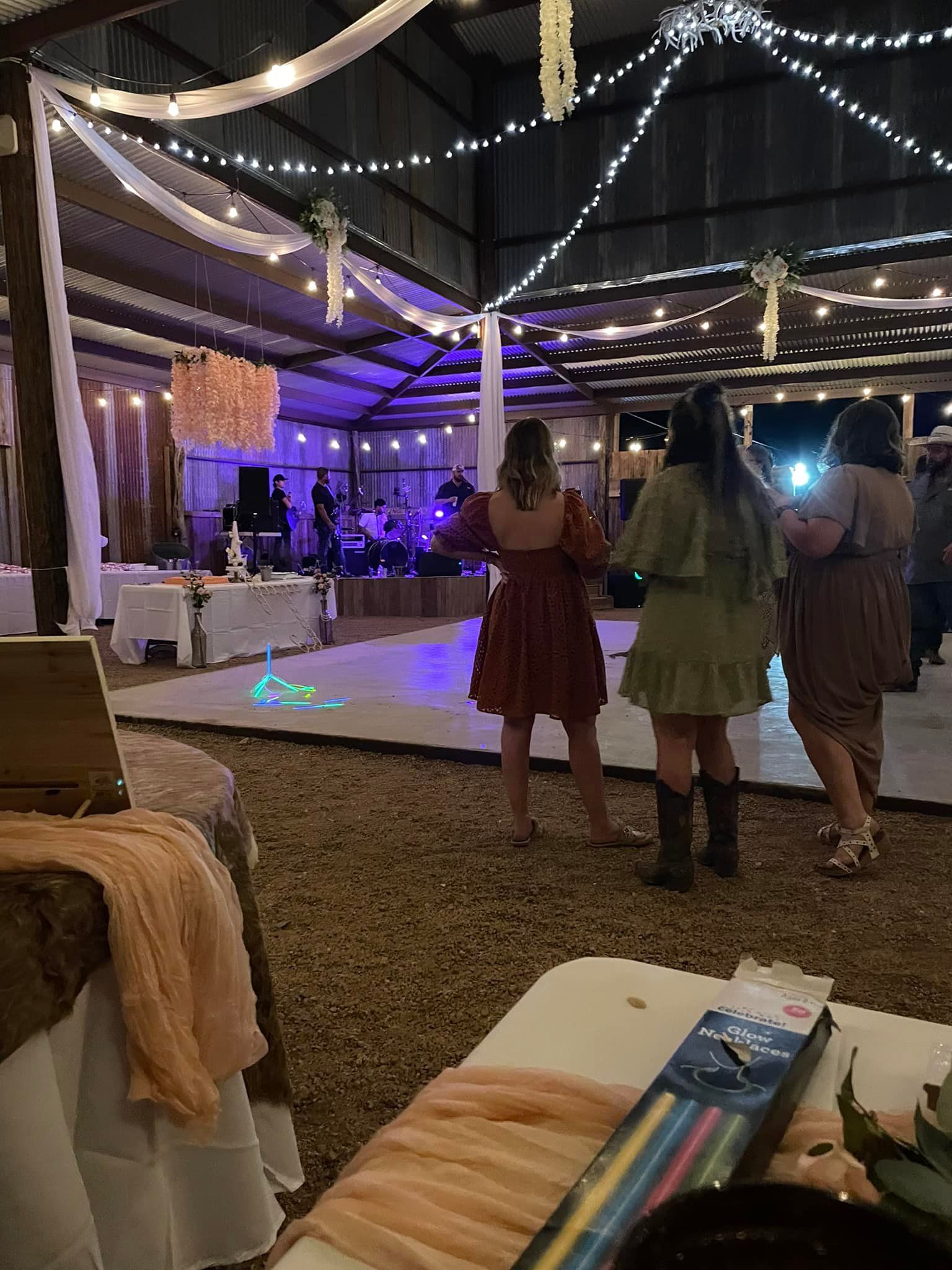 A group of women are standing on a dance floor at a wedding reception.