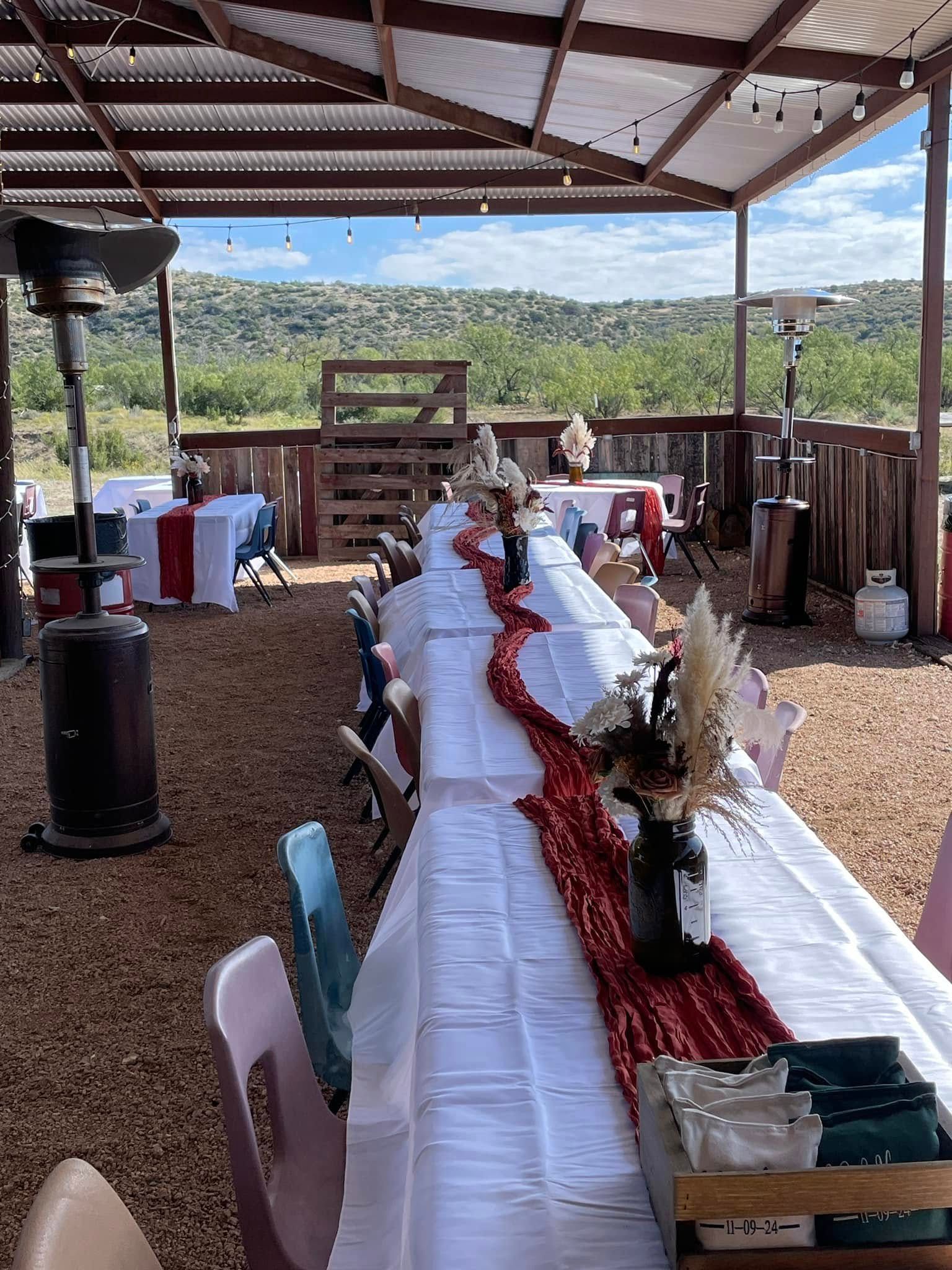 A long table with a red table runner is sitting under a canopy.