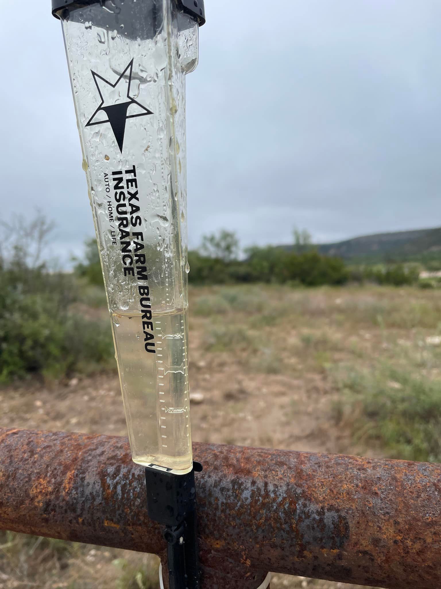 A rain gauge is sitting on top of a rusty pipe.