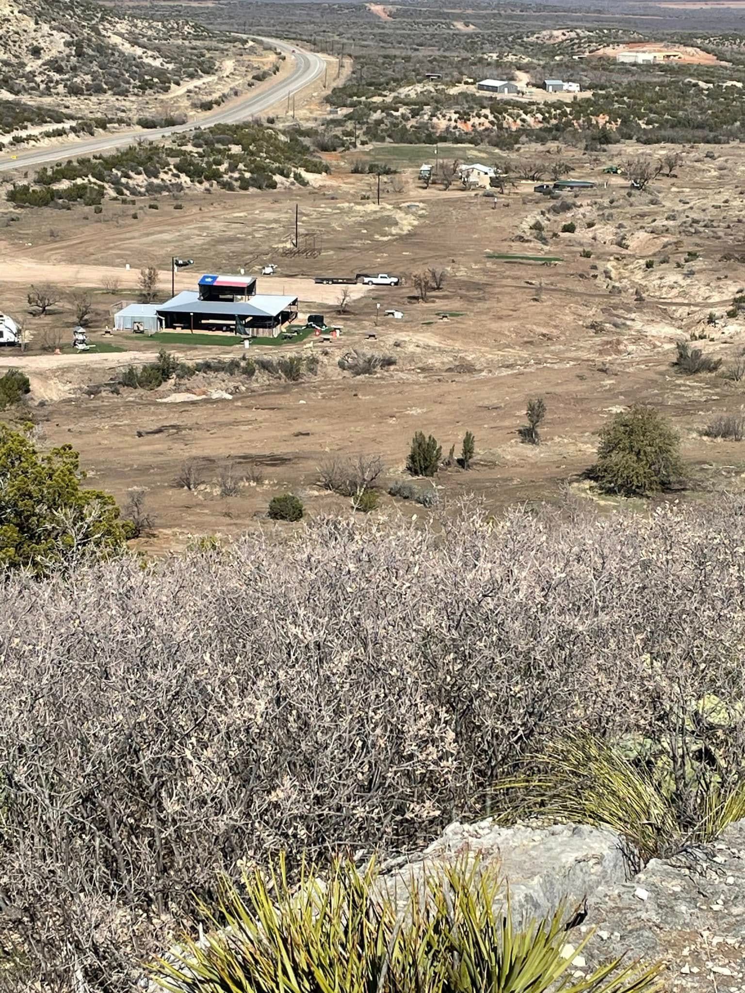 An aerial view of a desert landscape with a house in the distance.