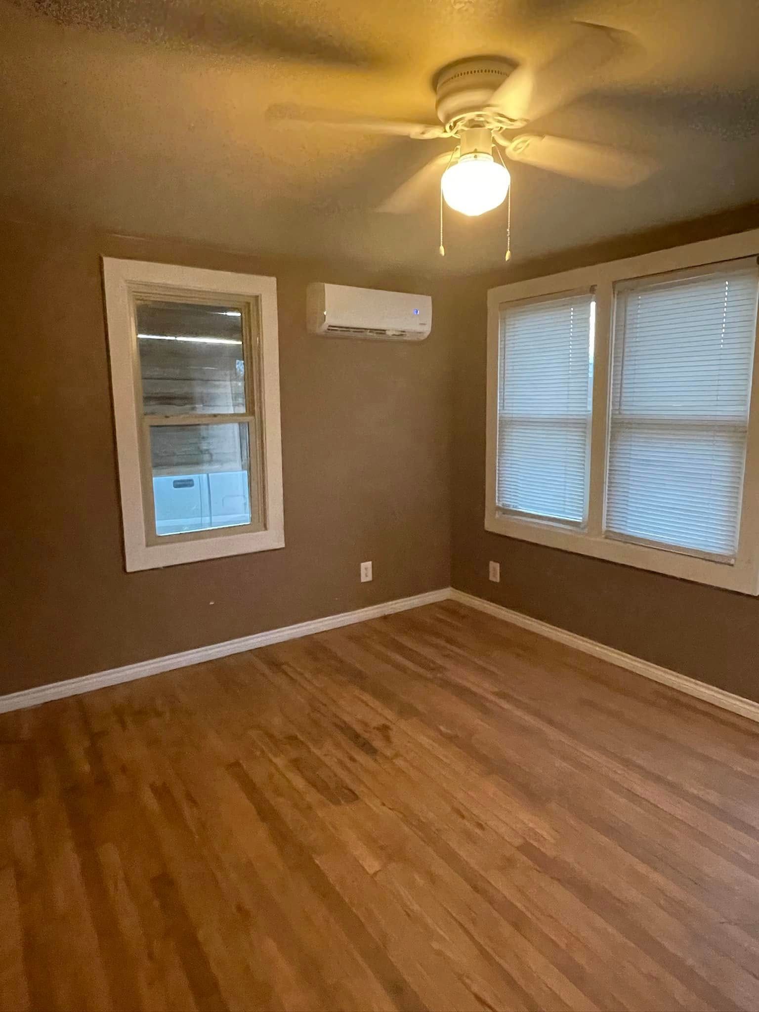 An empty room with hardwood floors and a ceiling fan.