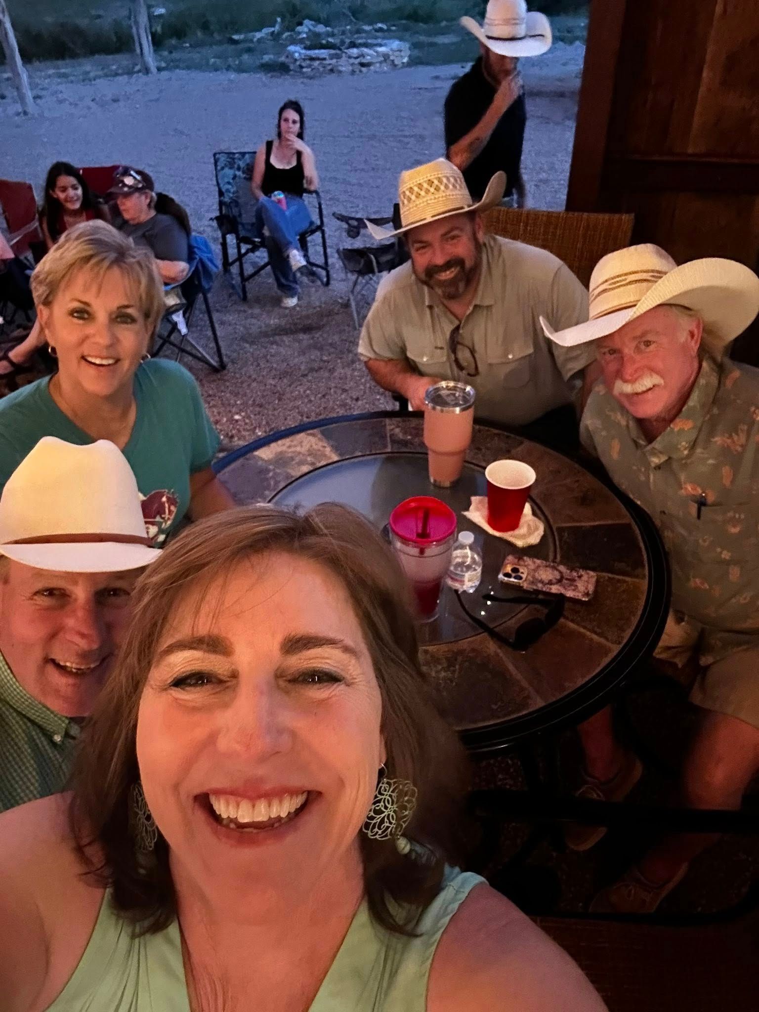 A group of people are sitting around a table taking a selfie.