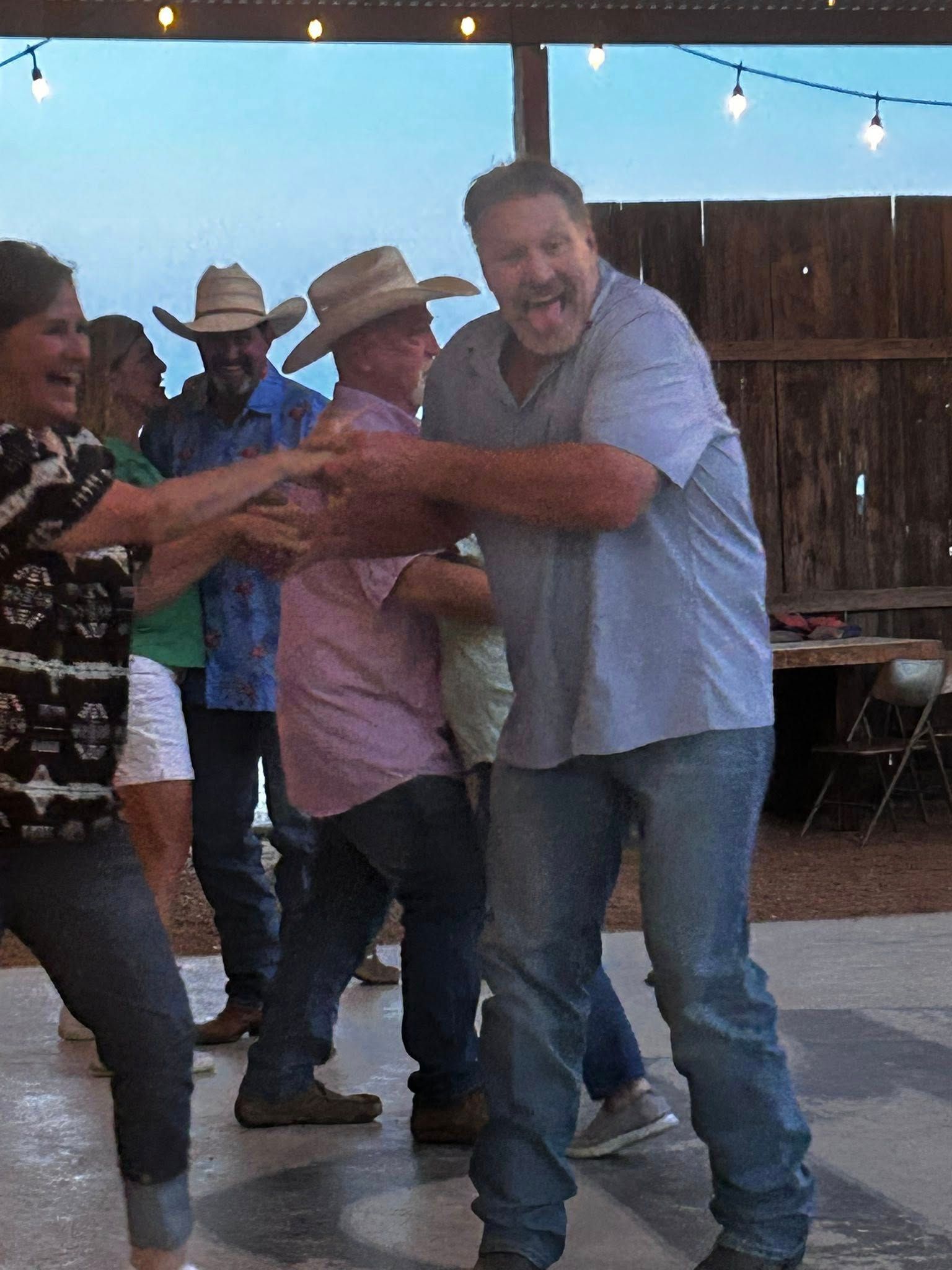 A group of people are dancing together and one of them is wearing a cowboy hat