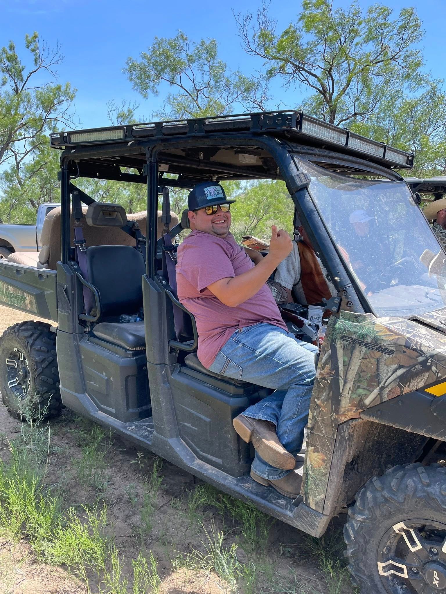 A man is sitting in the driver 's seat of a utility vehicle.