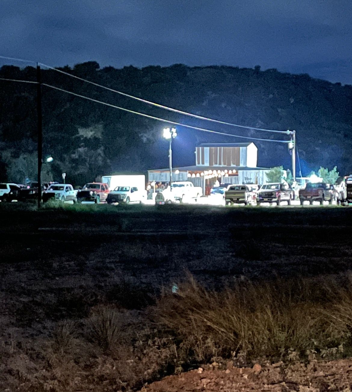 A lot of cars are parked in front of a building that says ' bar ' on it