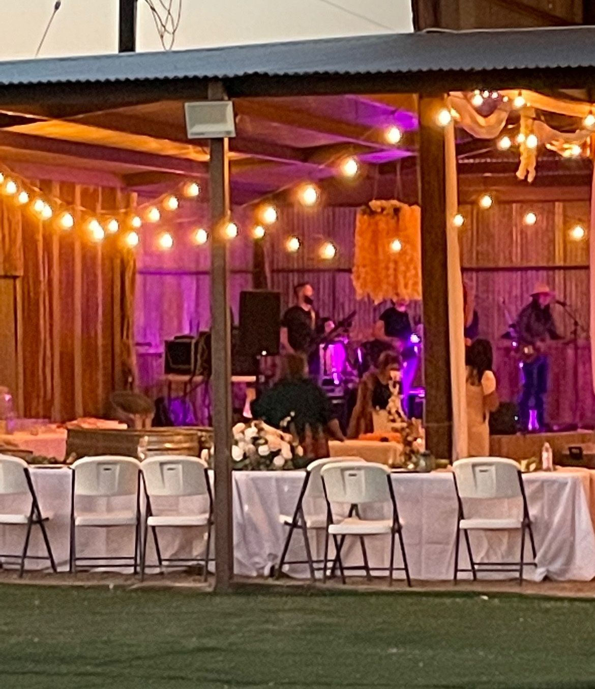 A group of people are sitting at tables under a covered area.
