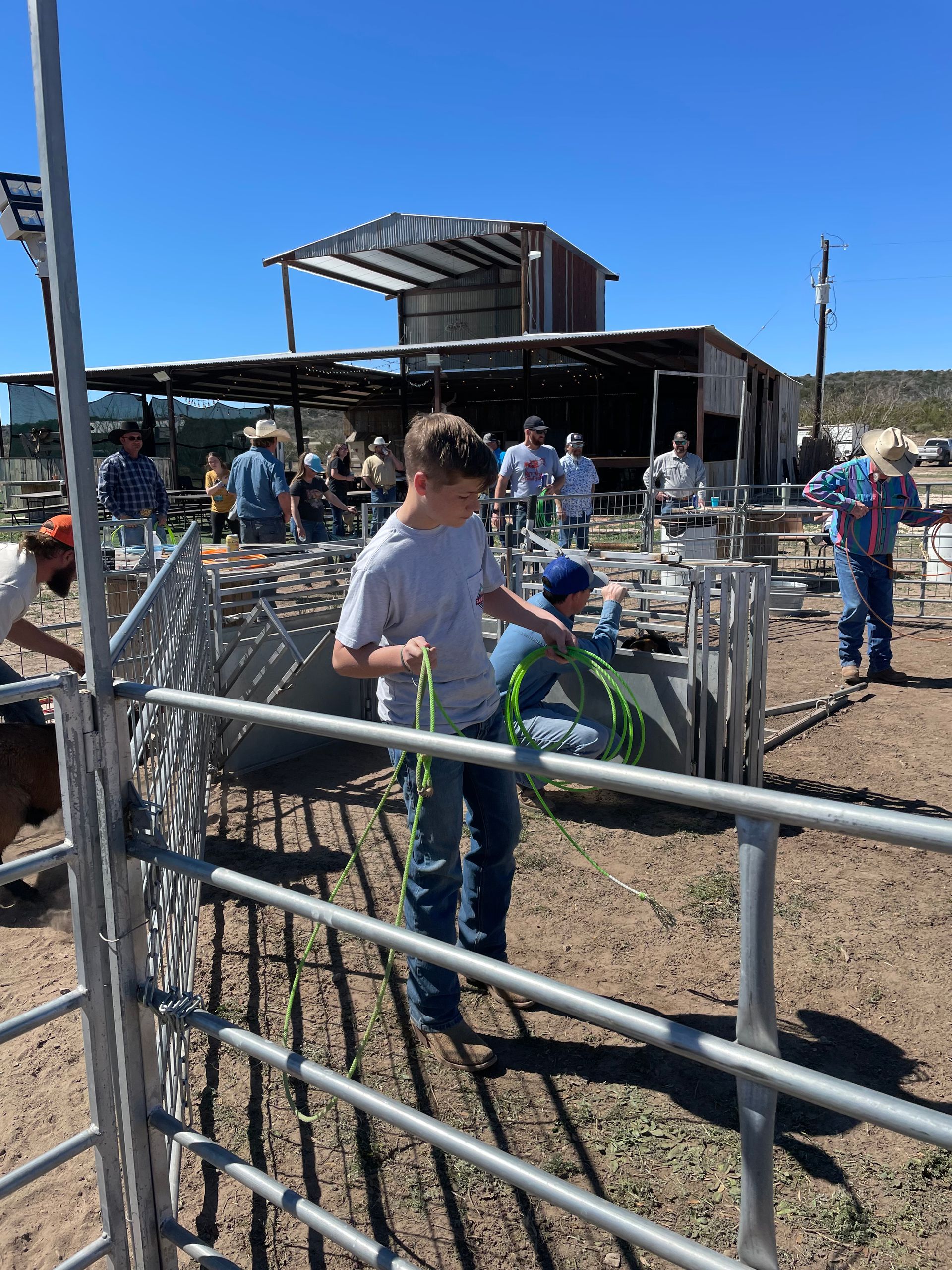 A boy is standing in a fenced in area holding a rope.