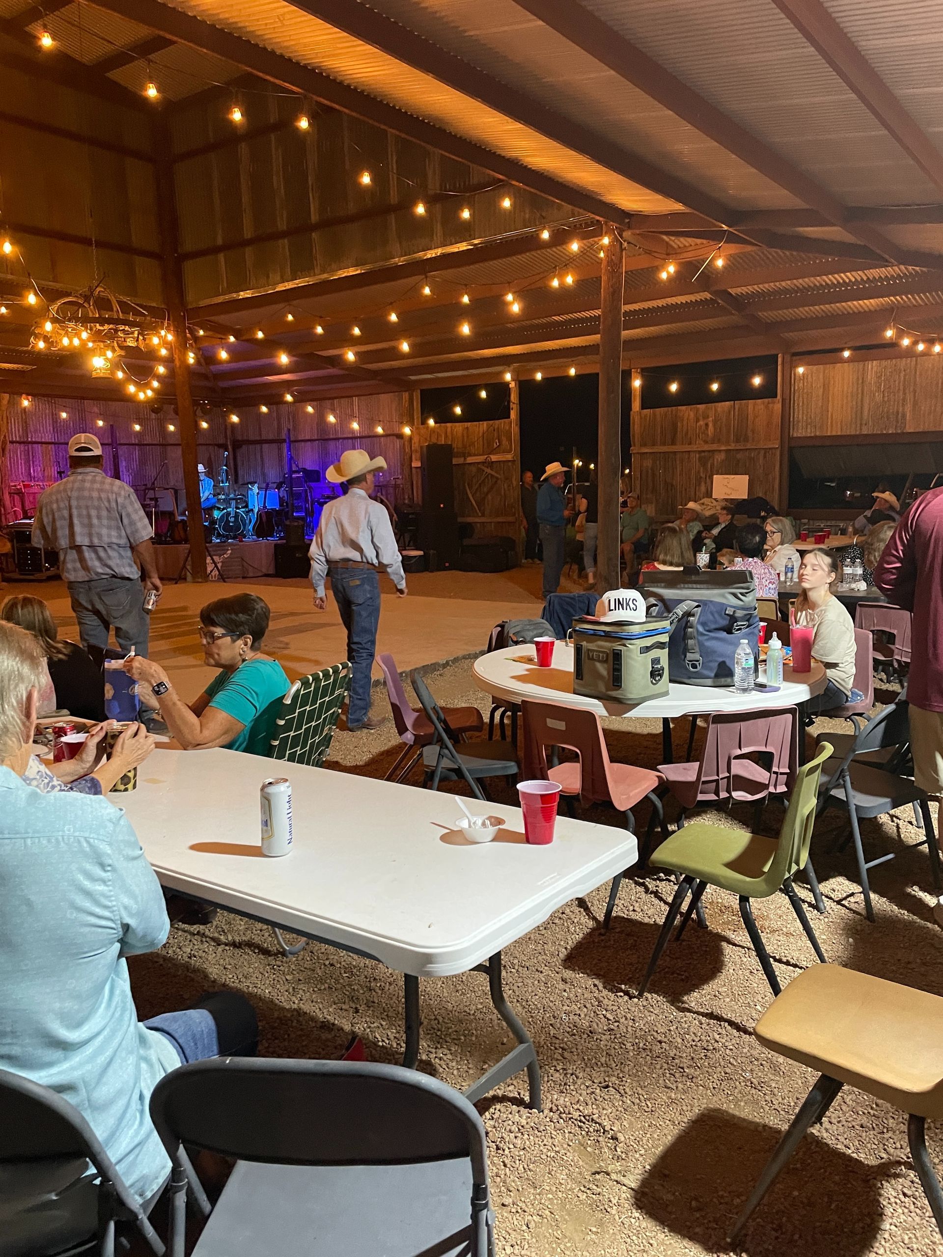 A group of people are sitting at tables in a barn.